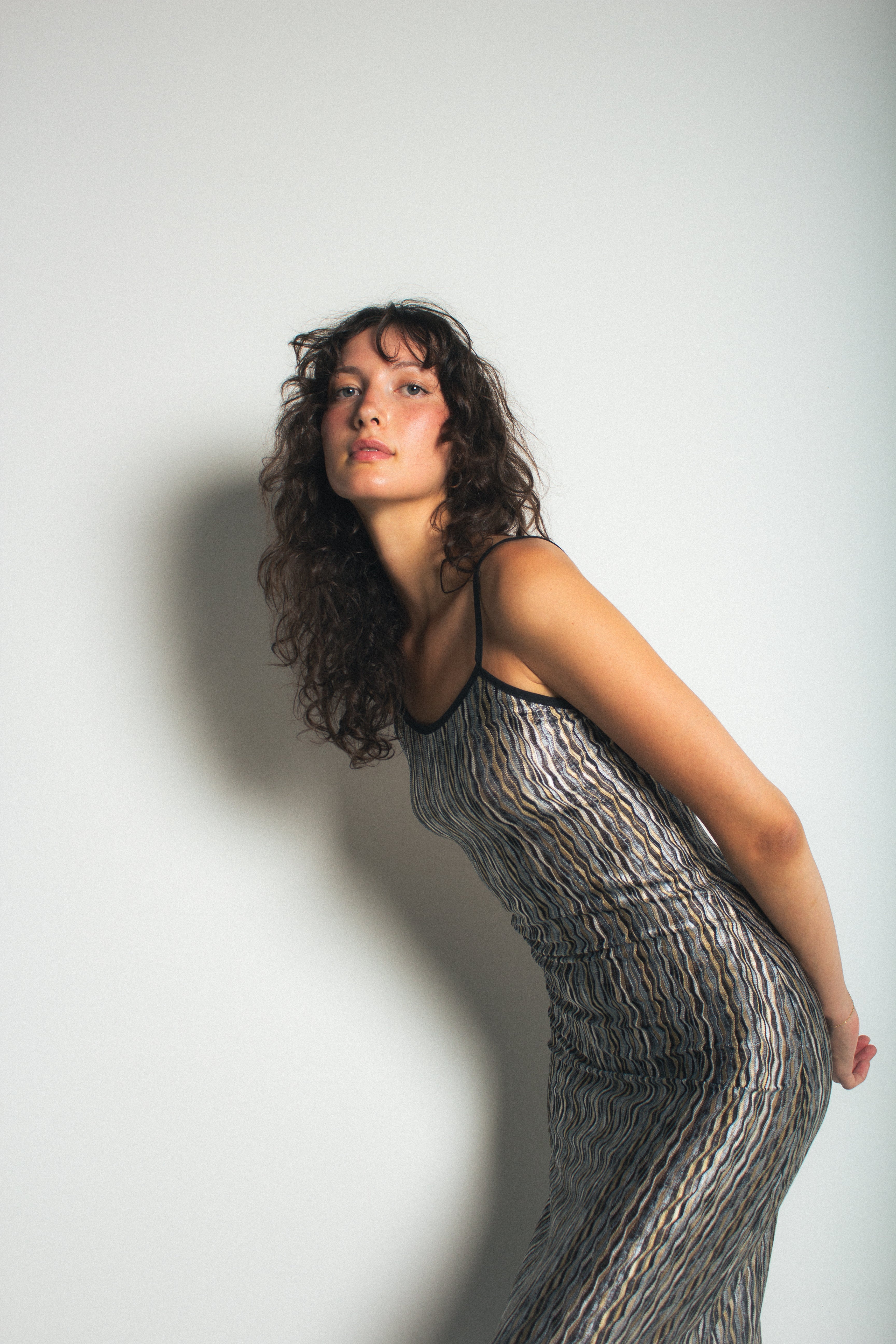 A model wearing the black naomi dress in a white background. 100% deadstock missoni-like, polyester knit blend.