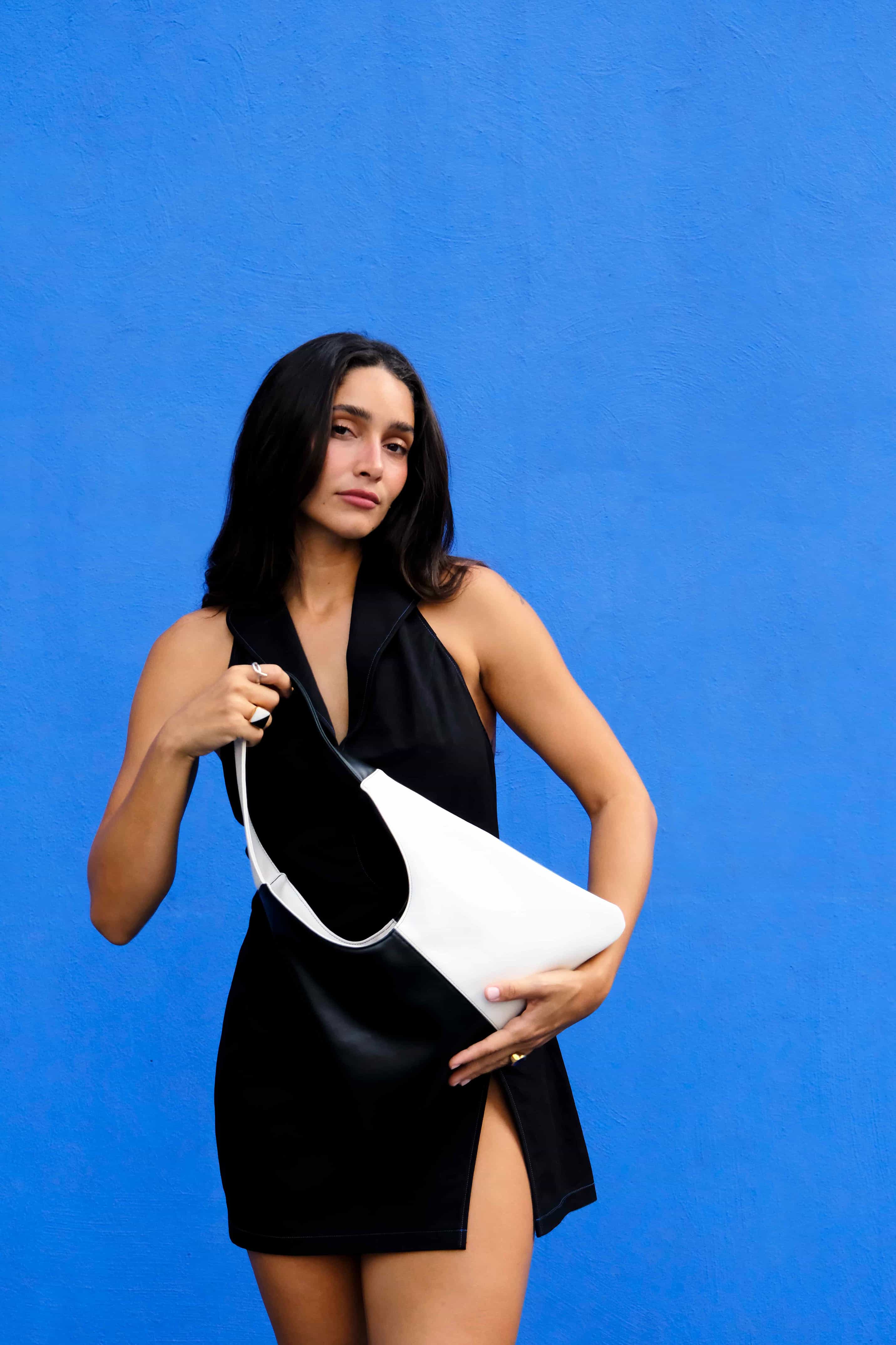 Woman holding a black and white tote made from cactus leather against a blue background