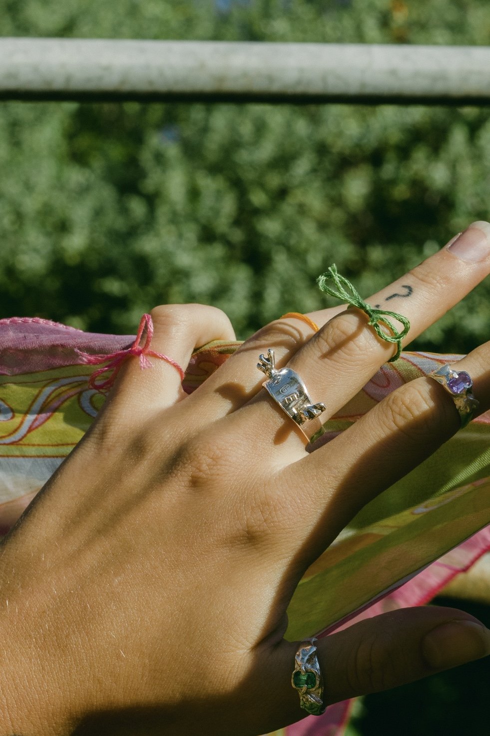 A hand model wearing the angel ring in a  outdoor background. Made from 100% recycled metals and lab created gemstones
