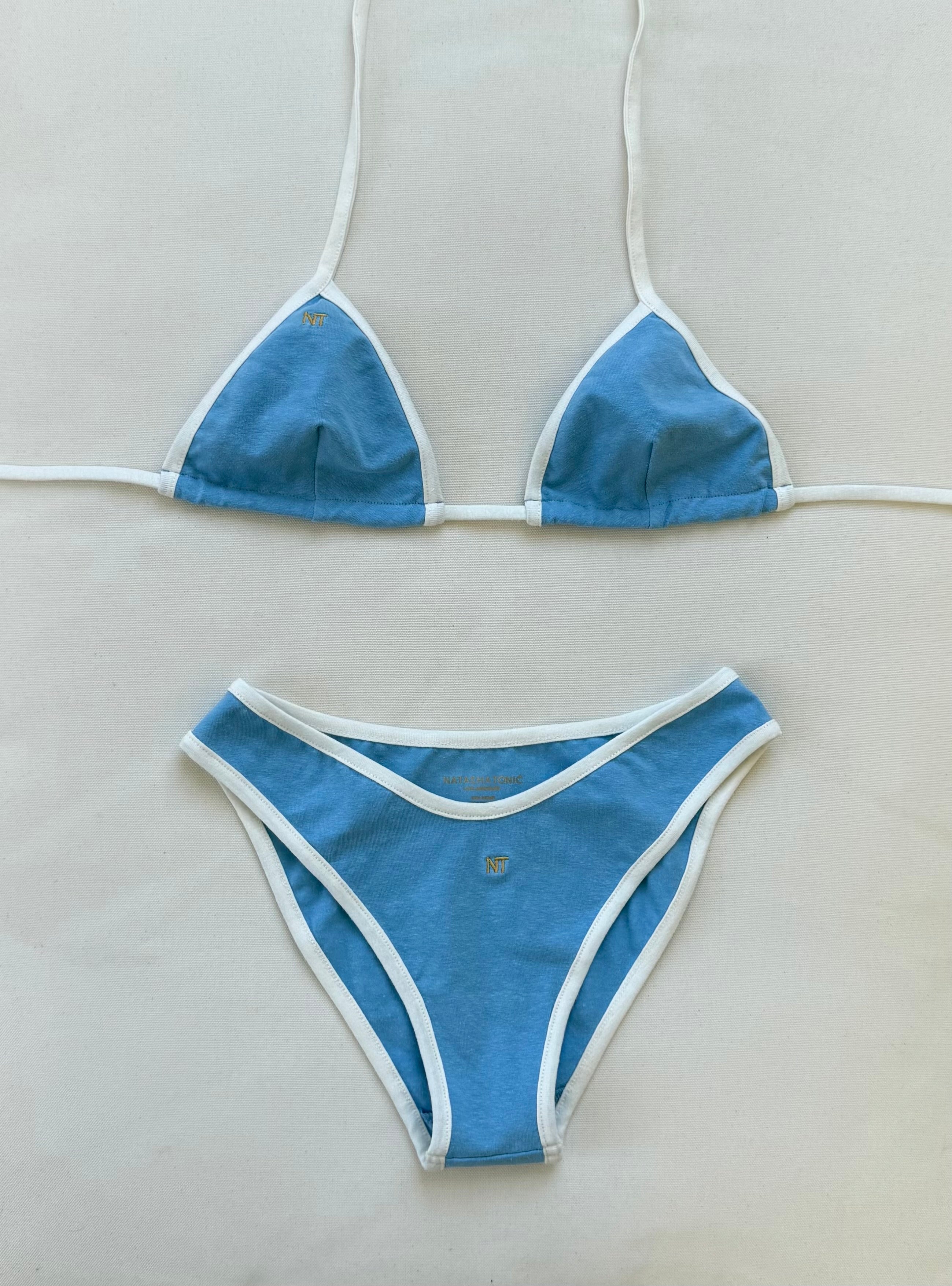 Blue sustainable bikini set with white trim on a light gray background