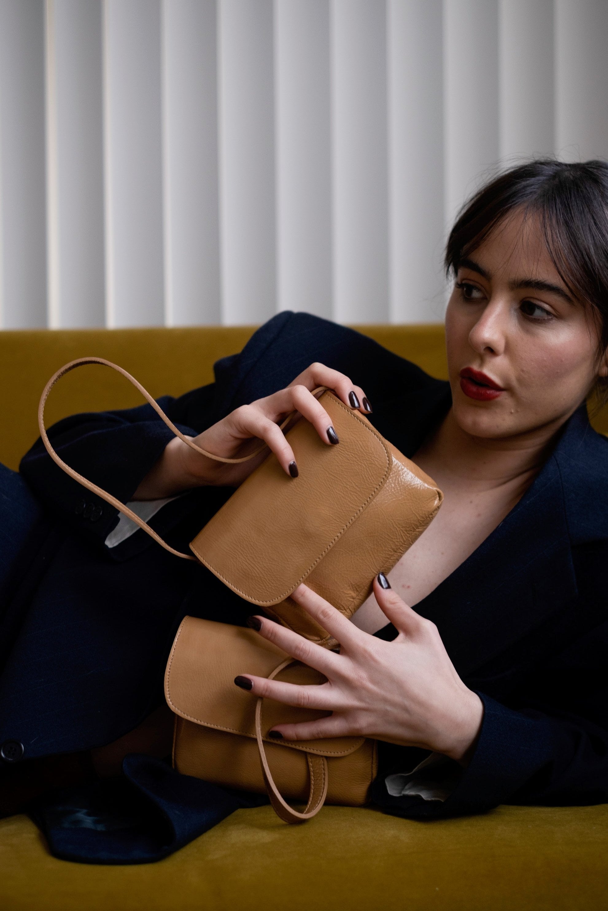 A model wearing the baby camel bag in an aesthetically background. 100% made from deadstock leather. 