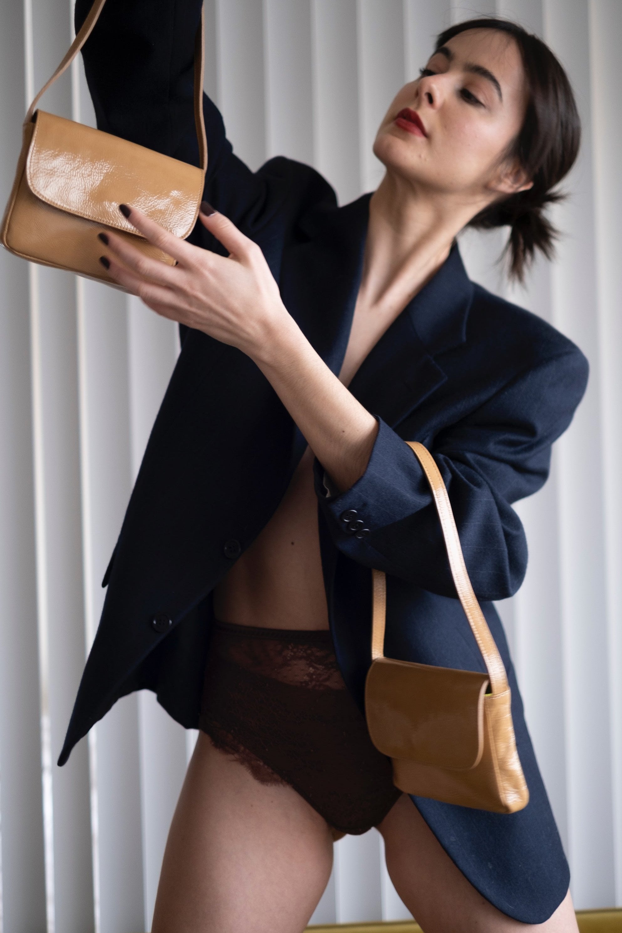 A model wearing the baby camel bag in an aesthetically background. 100% made from deadstock leather. 