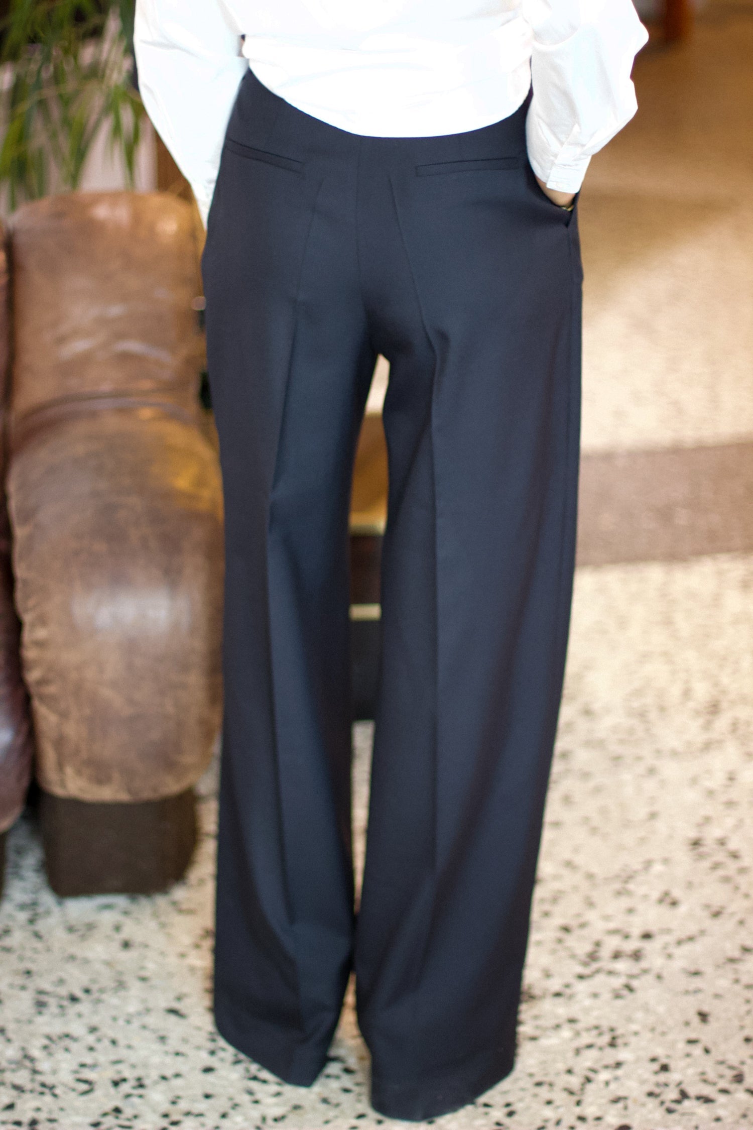 Close-up of a model wearing the bianca charcoal wool pants in an aesthetically background. 100% made from upcycled wool. 