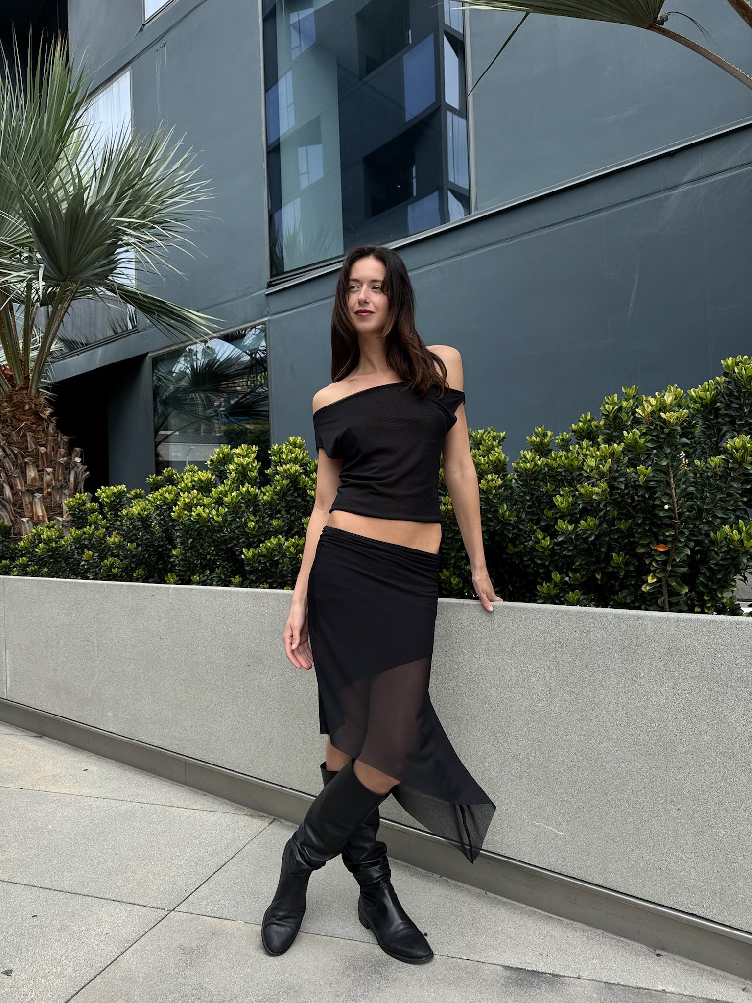 A model wearing the black city skirt in an aesthetically background. 100% made from sustainable deadstock materials.