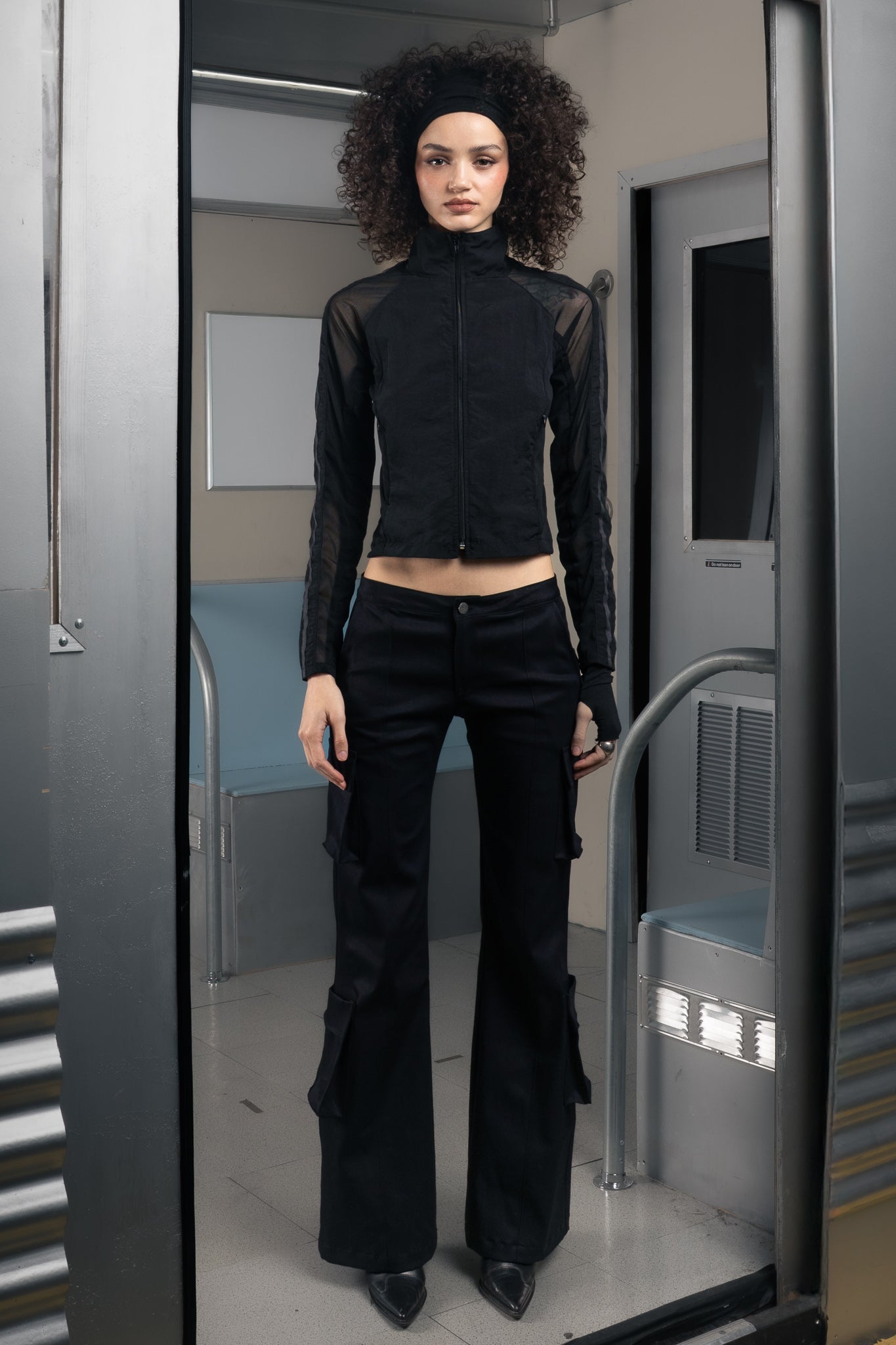 Woman wearing a sustainable black outfit standing in a futuristic train.