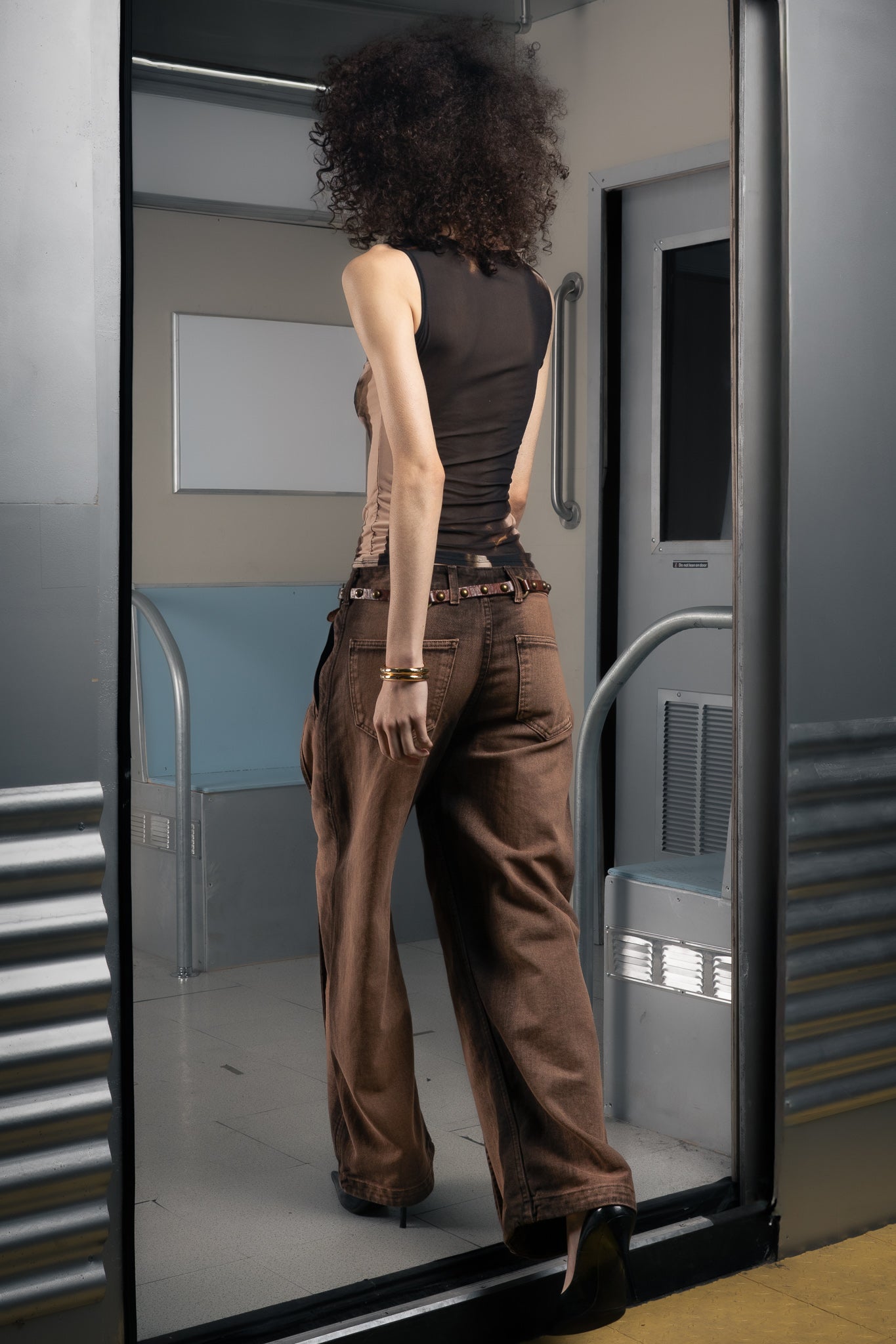 Woman standing in a futuristic train wearing a sustainable black mesh top.