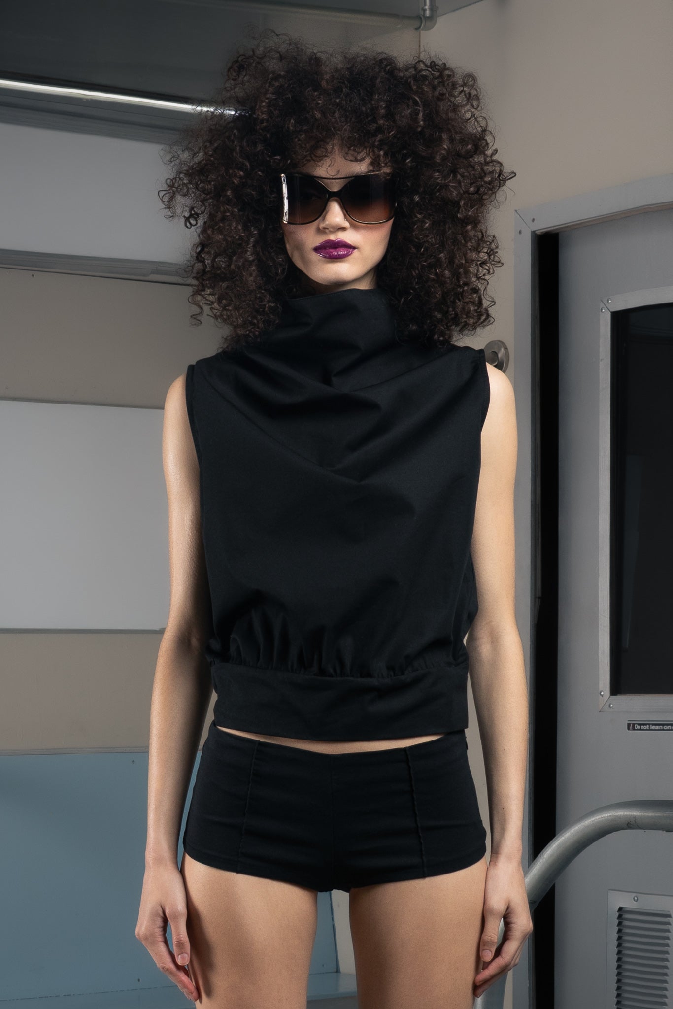 Person wearing a black sustainable sleeveless top and shorts in a futuristic setting