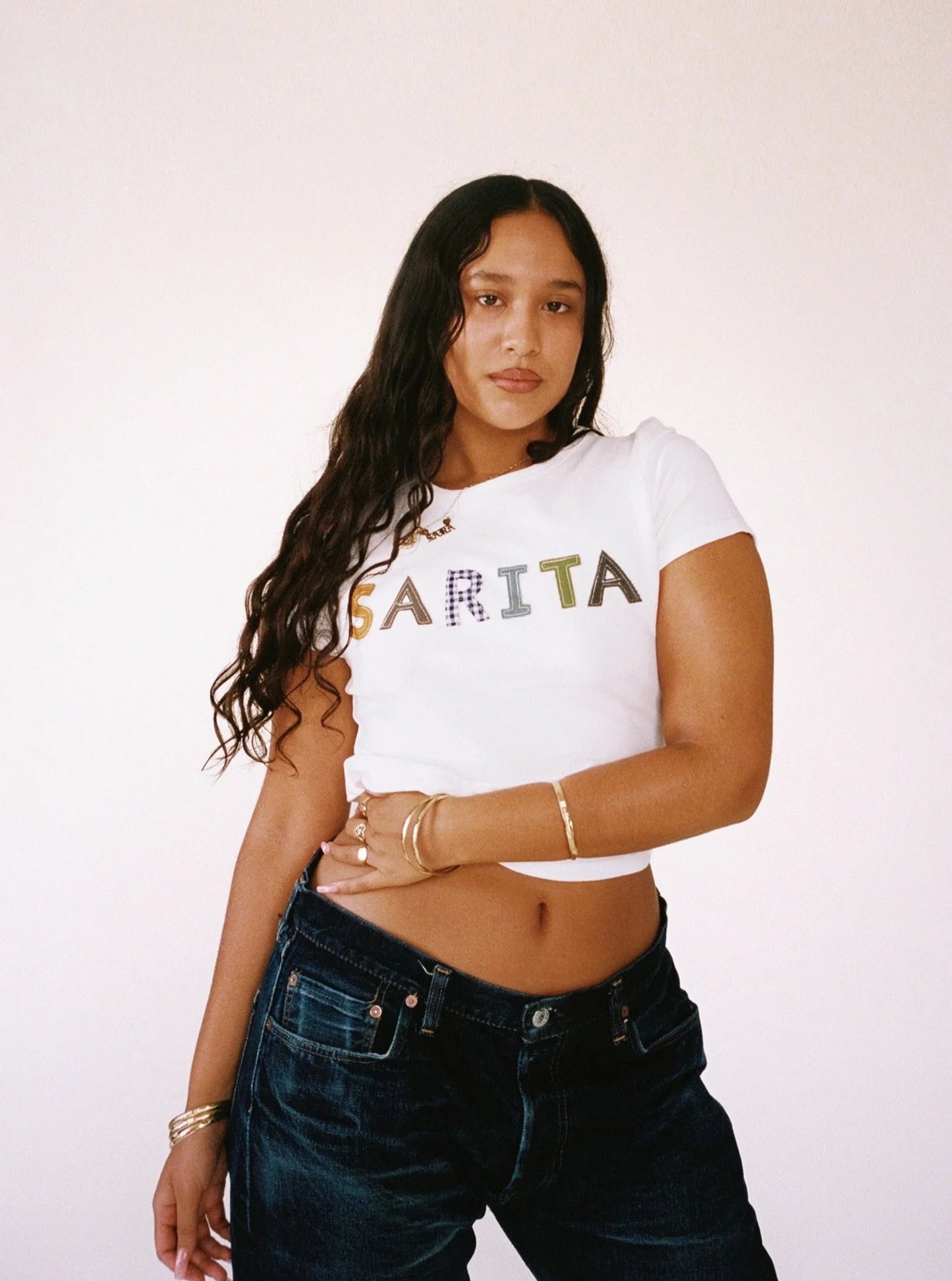 A model wearing the custom baby tee in a white background. Made from certified organic cotton and deadstock.