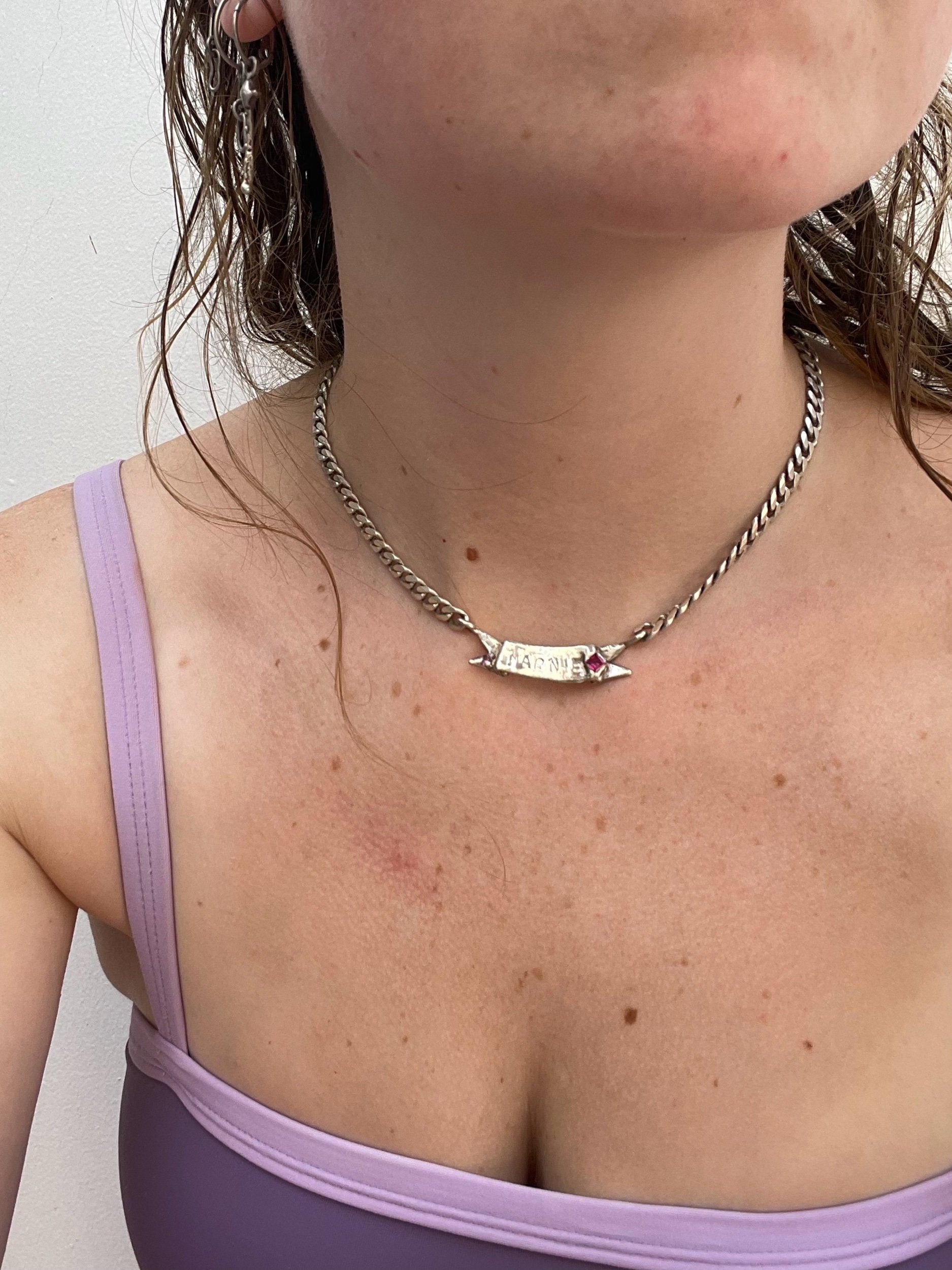 A model wearing the custom ribbon name necklace. Made from 100% recycled metals and lab created. gemstones. CLOSE UP