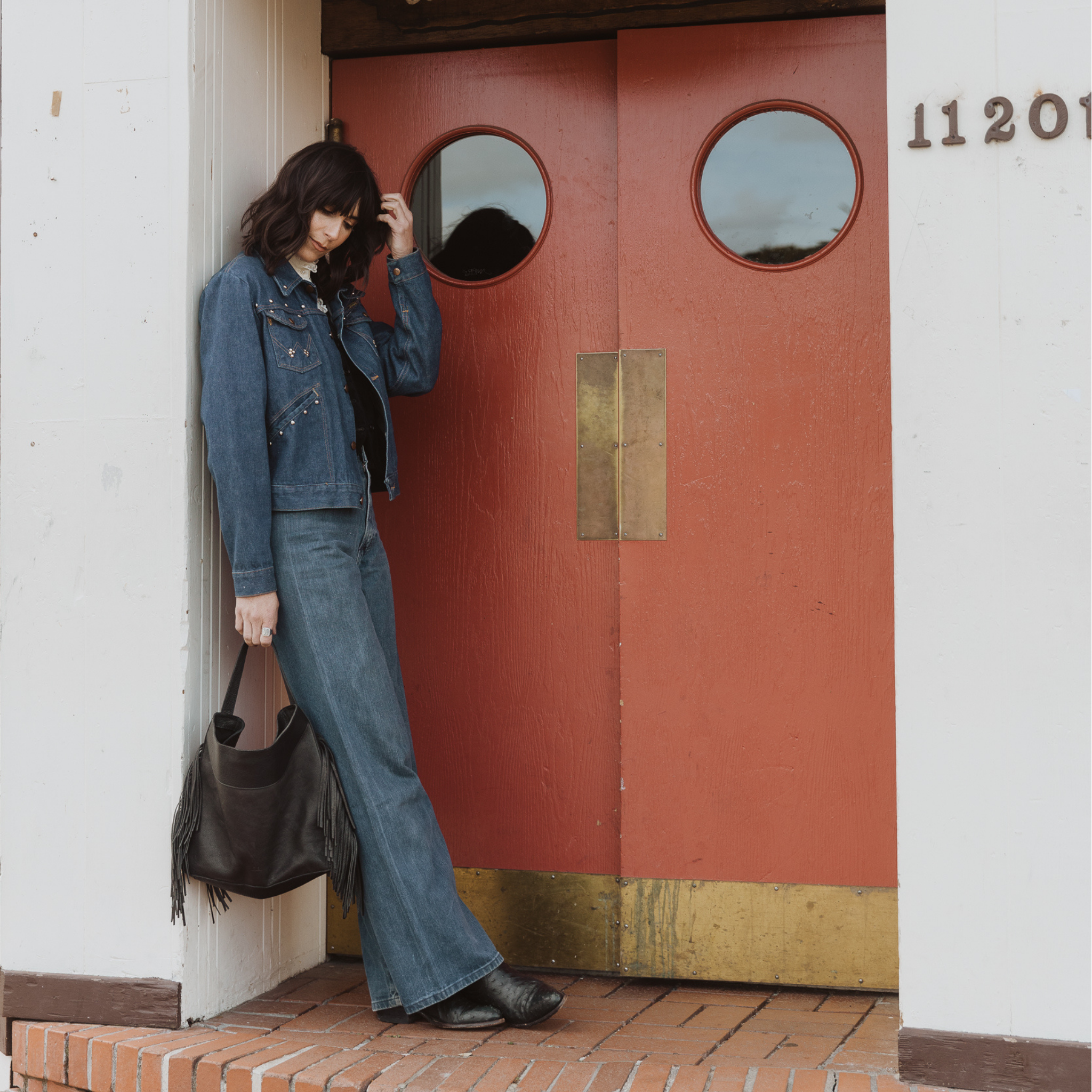 A model wearing the fringe hobo in an aesthetically background. Leathers are sourced from regenerative ranches.