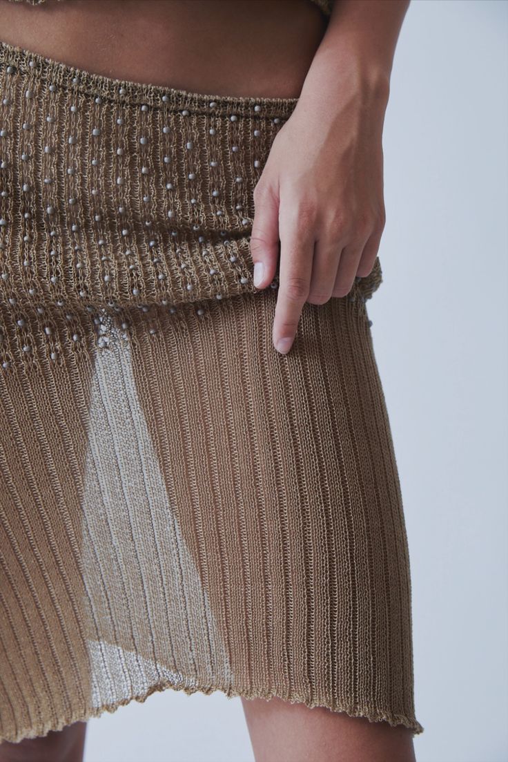 A model wearing the kie skirt in a white background. 100% beige cotton knit.