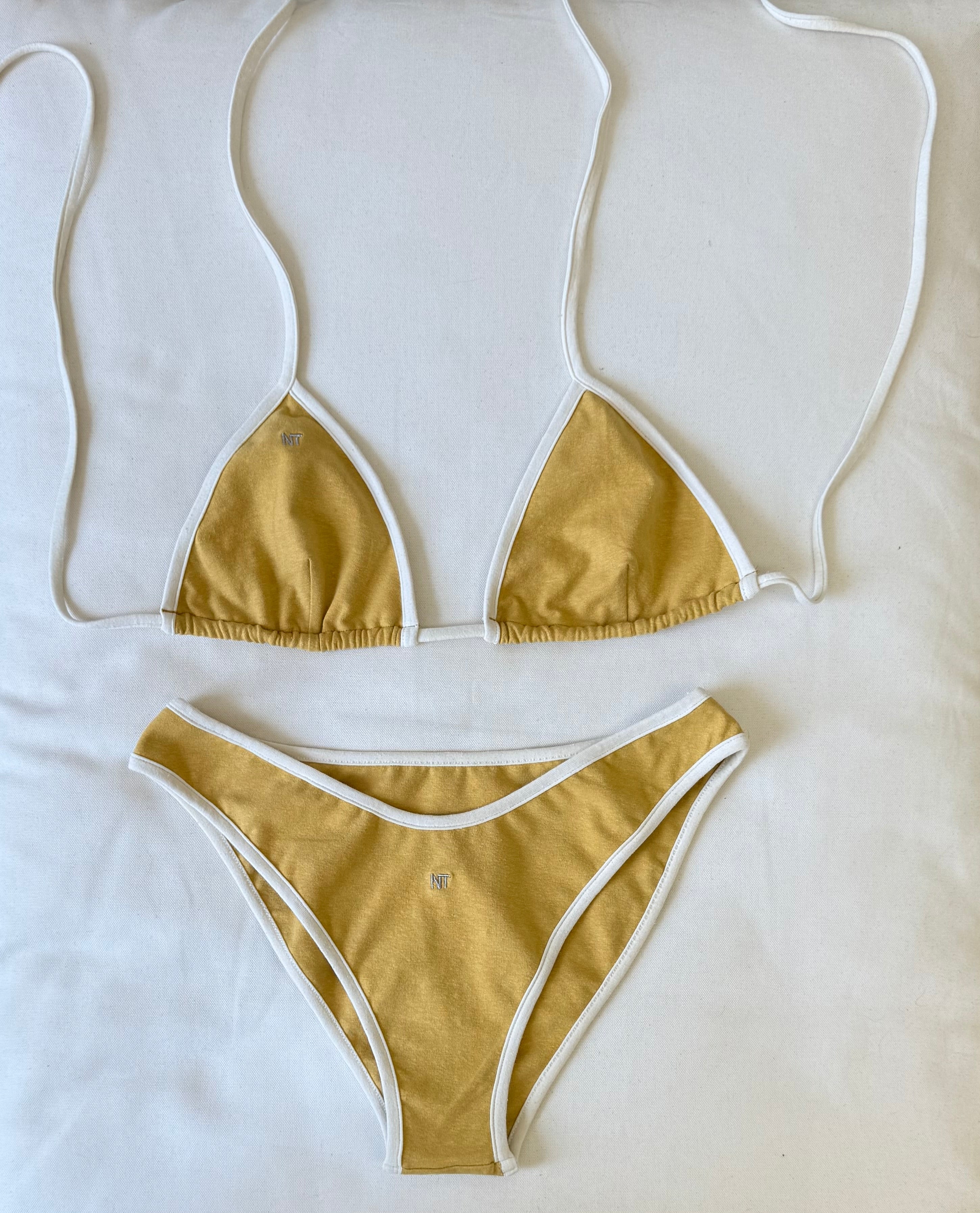 Yellow and white bikini top and bottom laying on the pillow. In organic cotton hemp. Lemon Zest Pasta Collection.