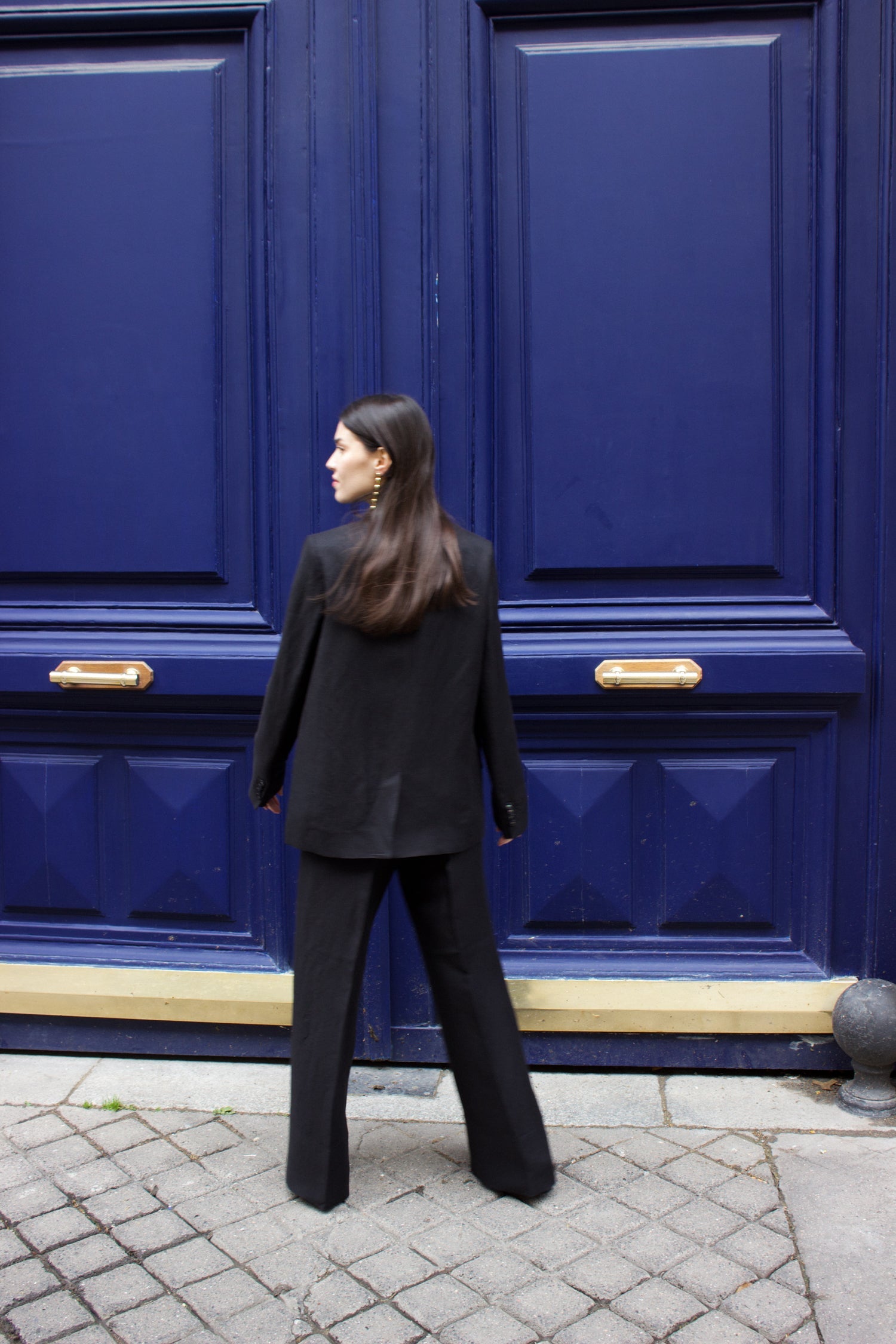 A model wearing the lauren black linen twill blazer in an aesthetically background. 100% upcycled GOTS certified linen.