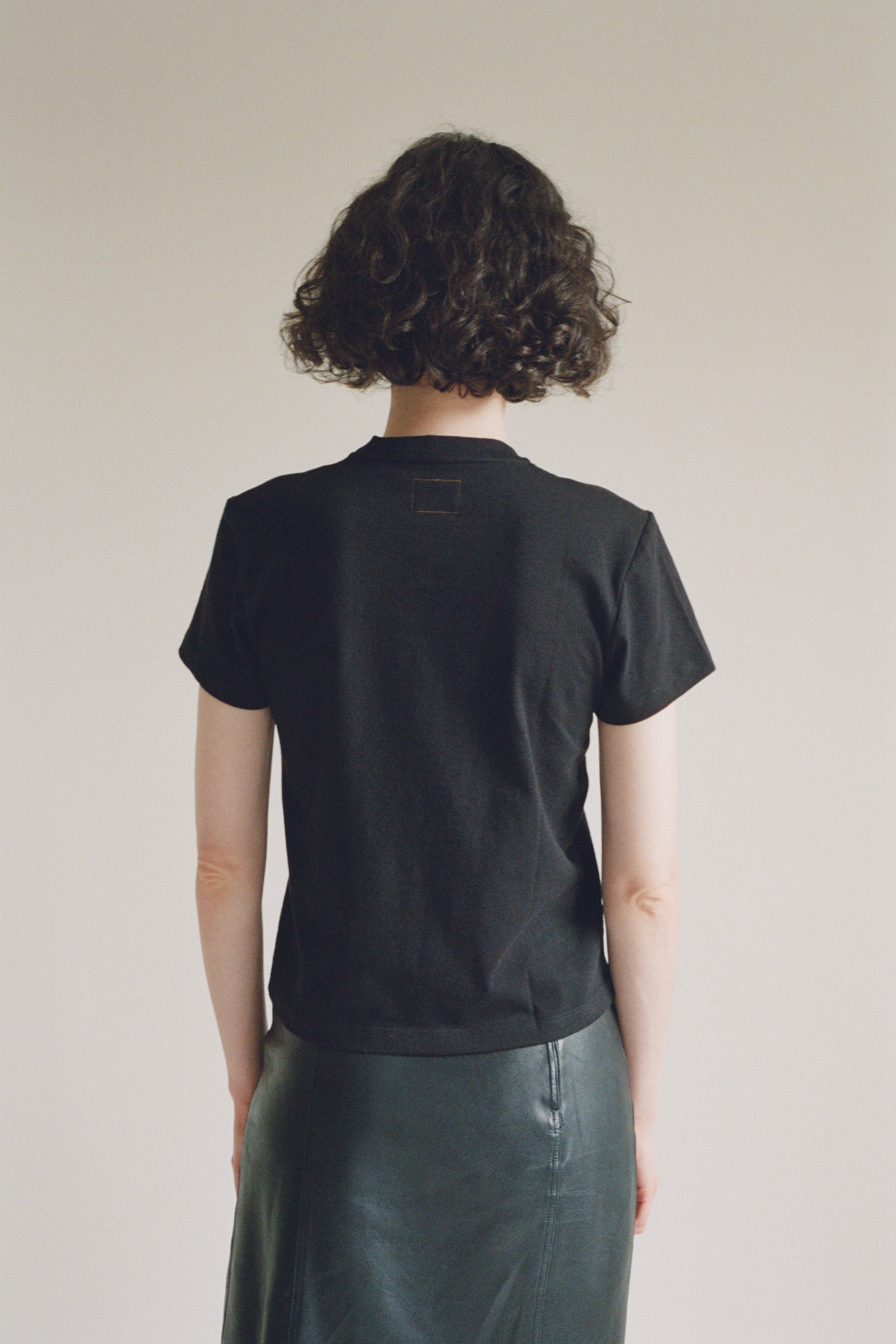 A model wearing the black little tshirt in a white background. 100% made from organic grown cotton. 