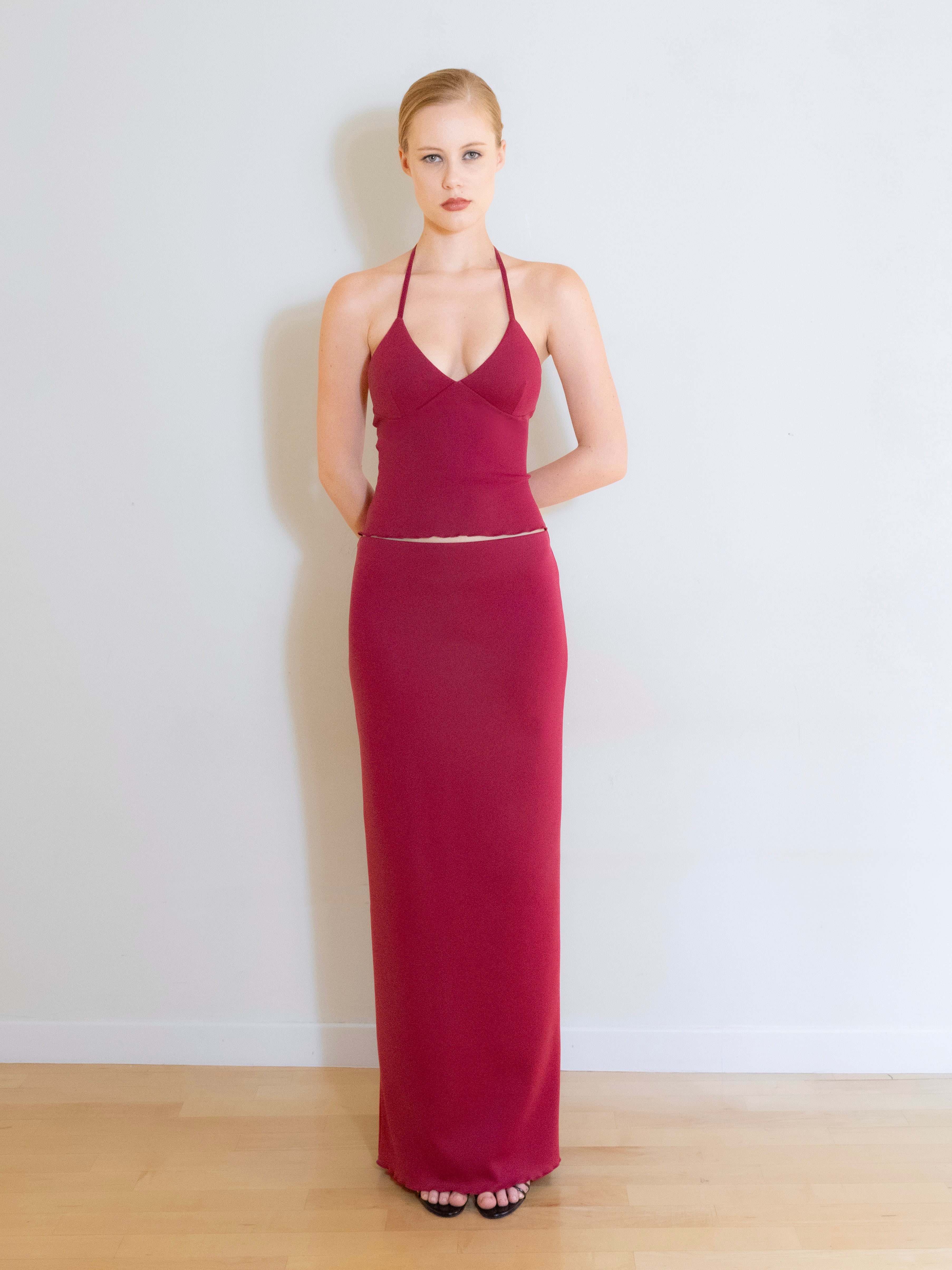 A model wearing the Luna knit maxi skirt in a white background. Made from soft, stretchy deadstock fabric