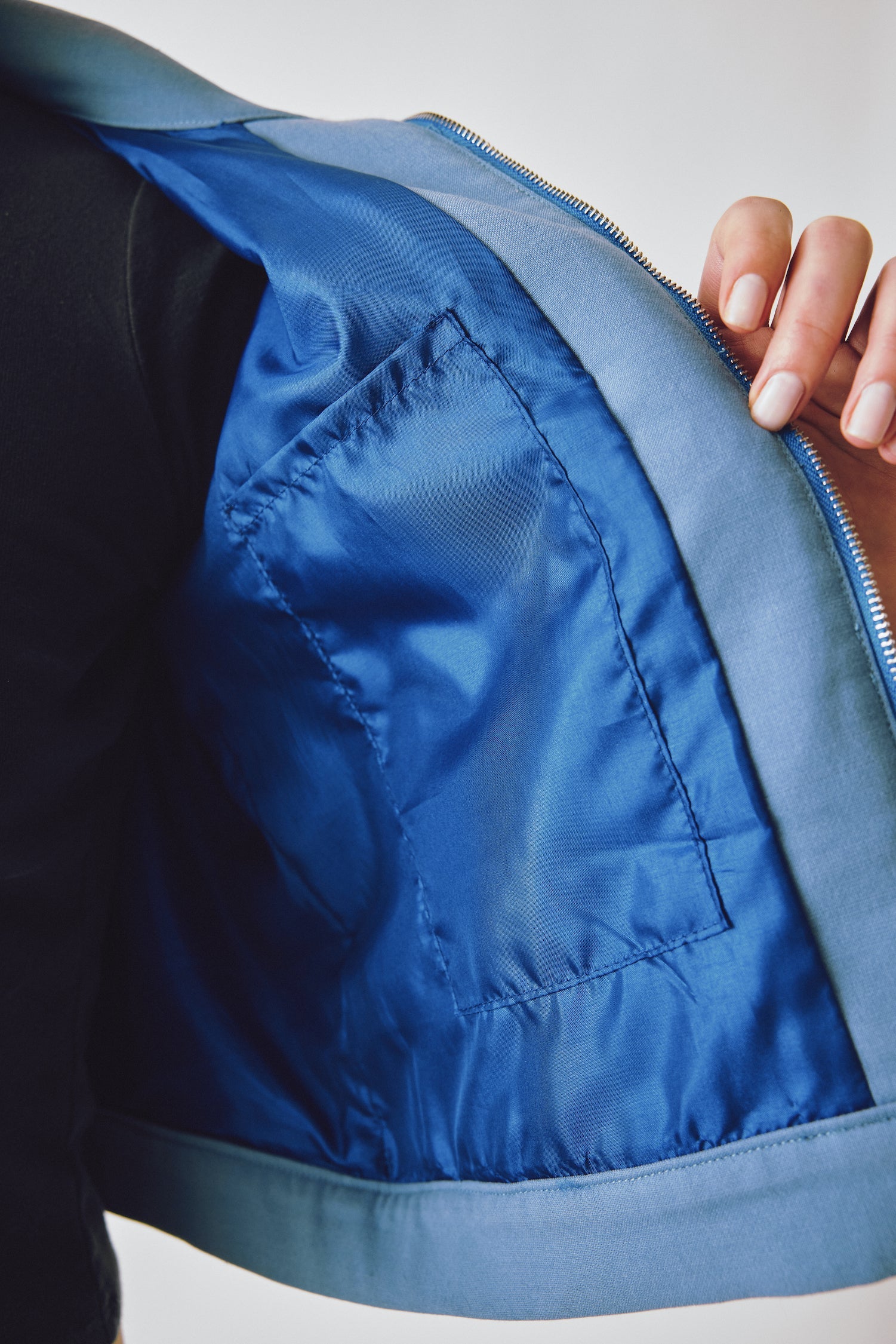 Close-up of the inside jacket of a model wearing the Miro Jacket in a white background. Deadstock wool blend with a recycled satin lining.