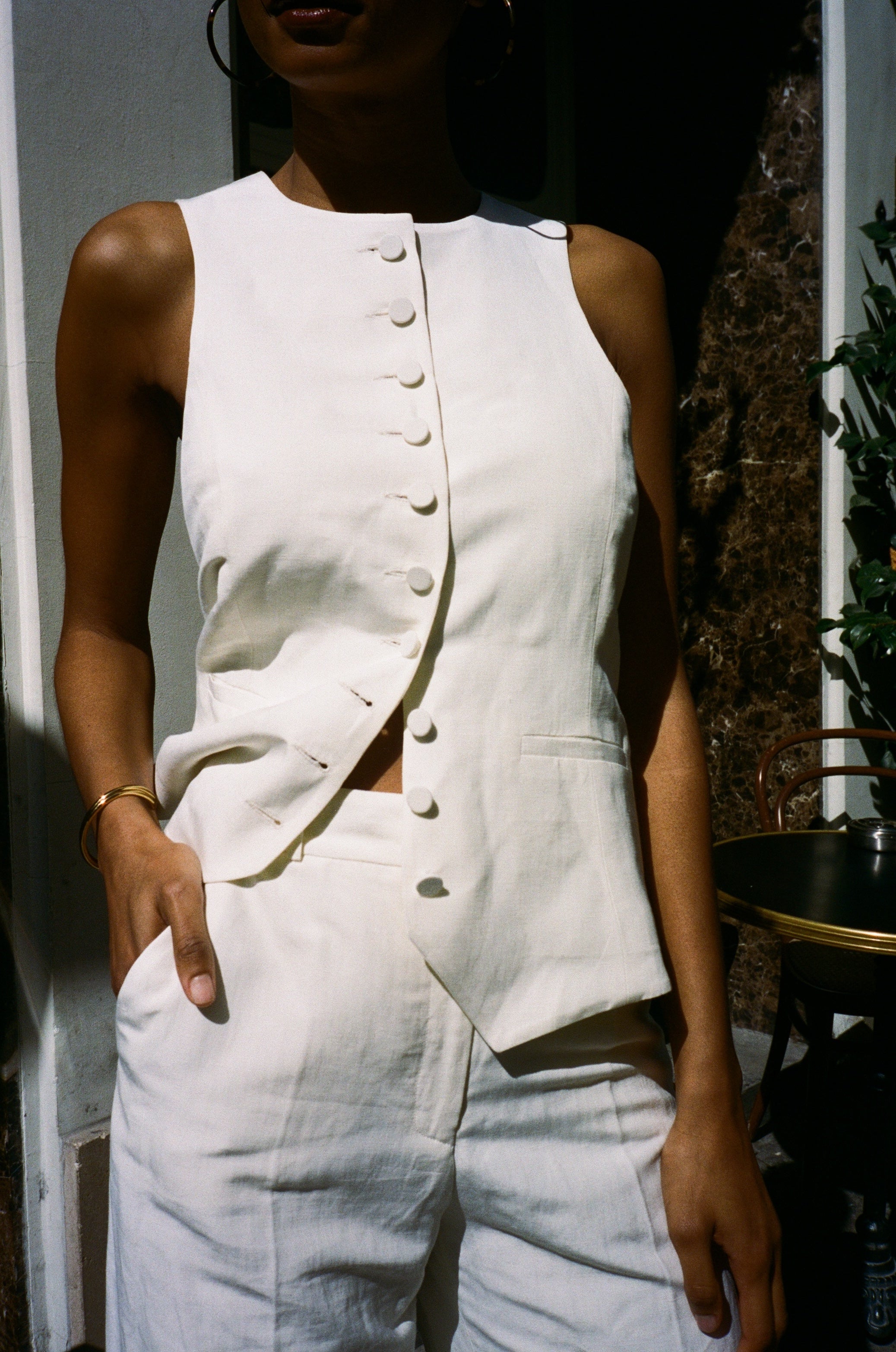A model wearing the monica off white vest in an aestheticaly background. 100% upcycled linen and silk mix.