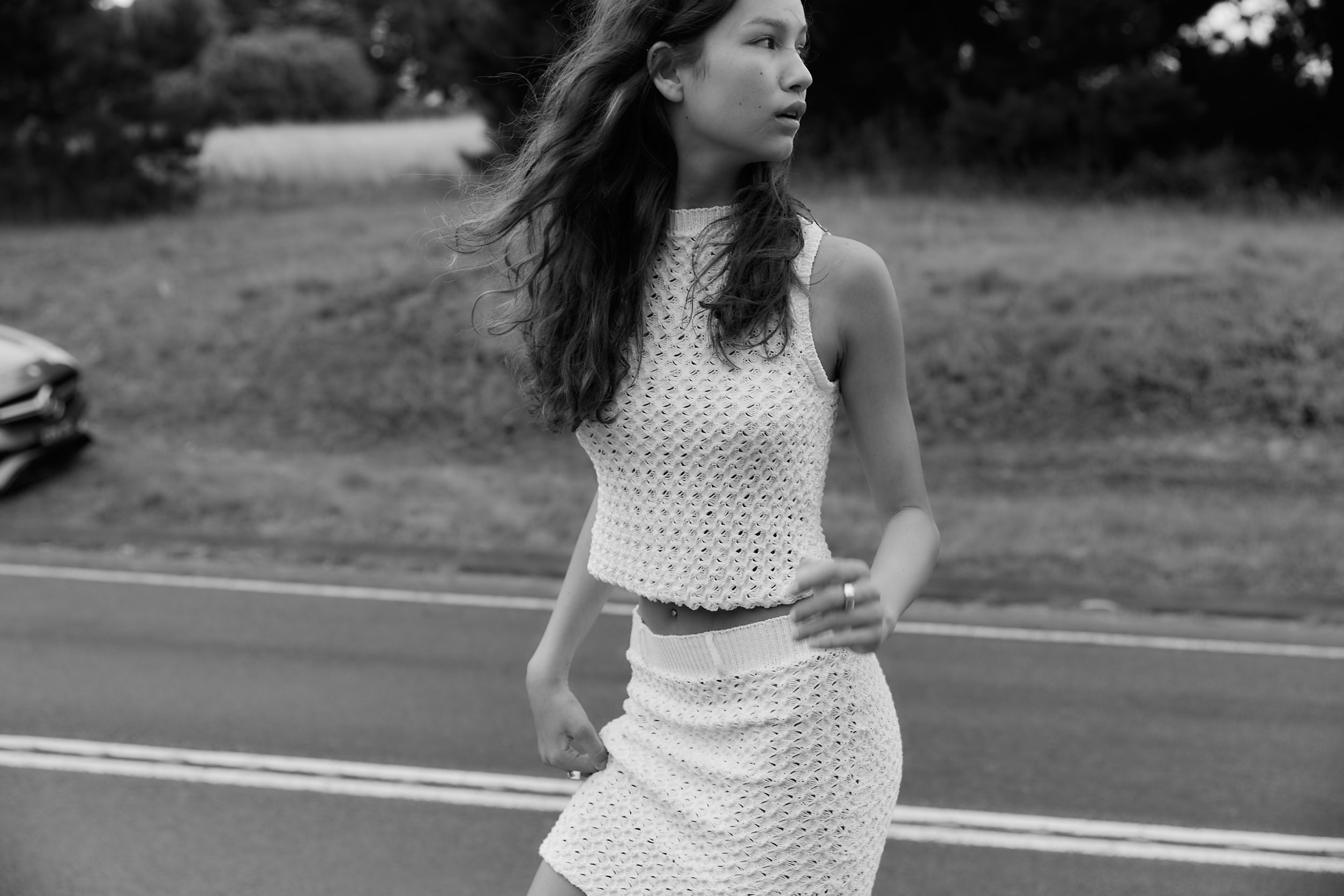 A model wearing the noa top in an aesthetically background. 100% white cotton knit.