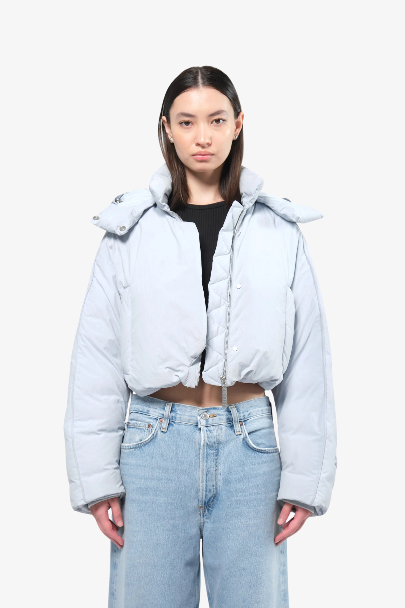 Model wearing a crop puffer in a white background. 100% made from recycled fabric. 