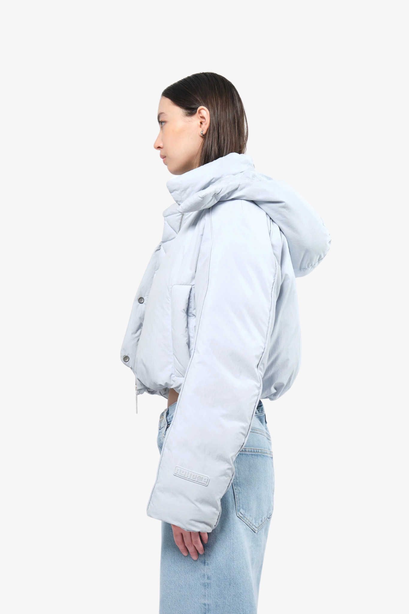 Model wearing a crop puffer in a white background. 100% made from recycled fabric. 