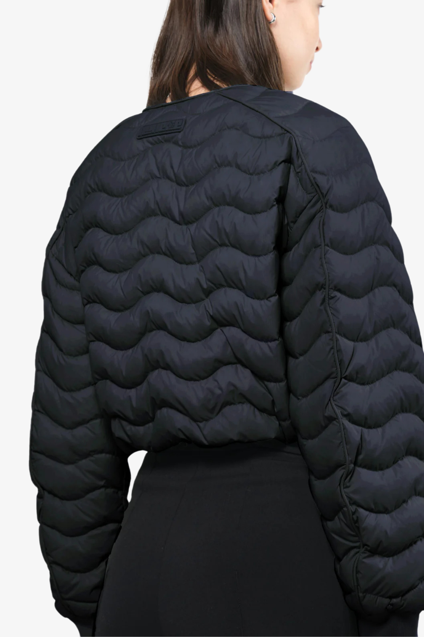 Model wearing a light crop puffer jacket in a white background. 100% made from recycled fabric. 