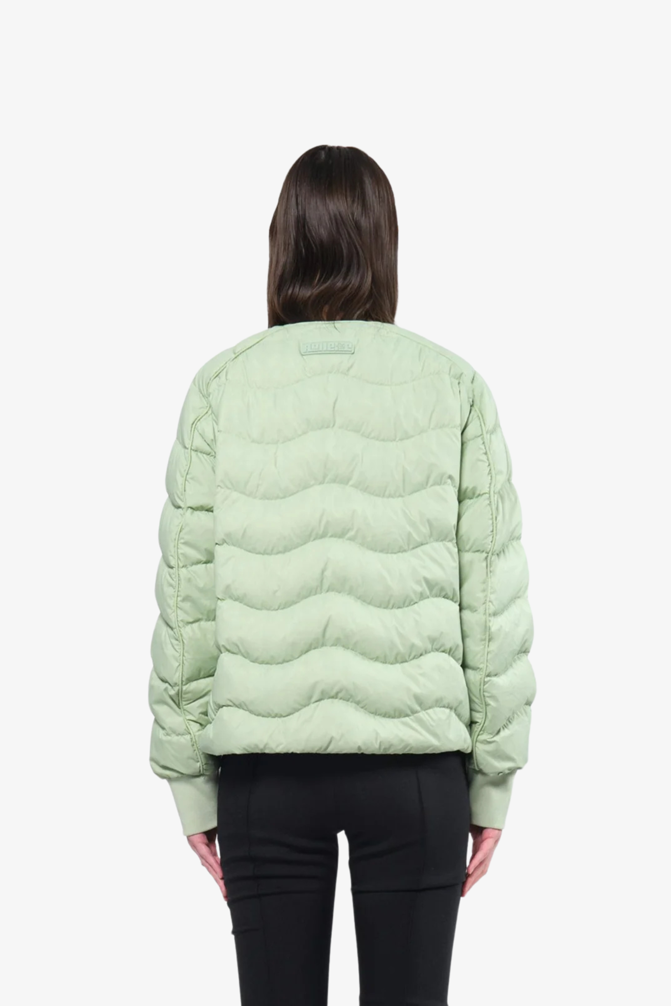 Model wearing a light puffer jacket in a white background. 100% made from recycled fabric. 