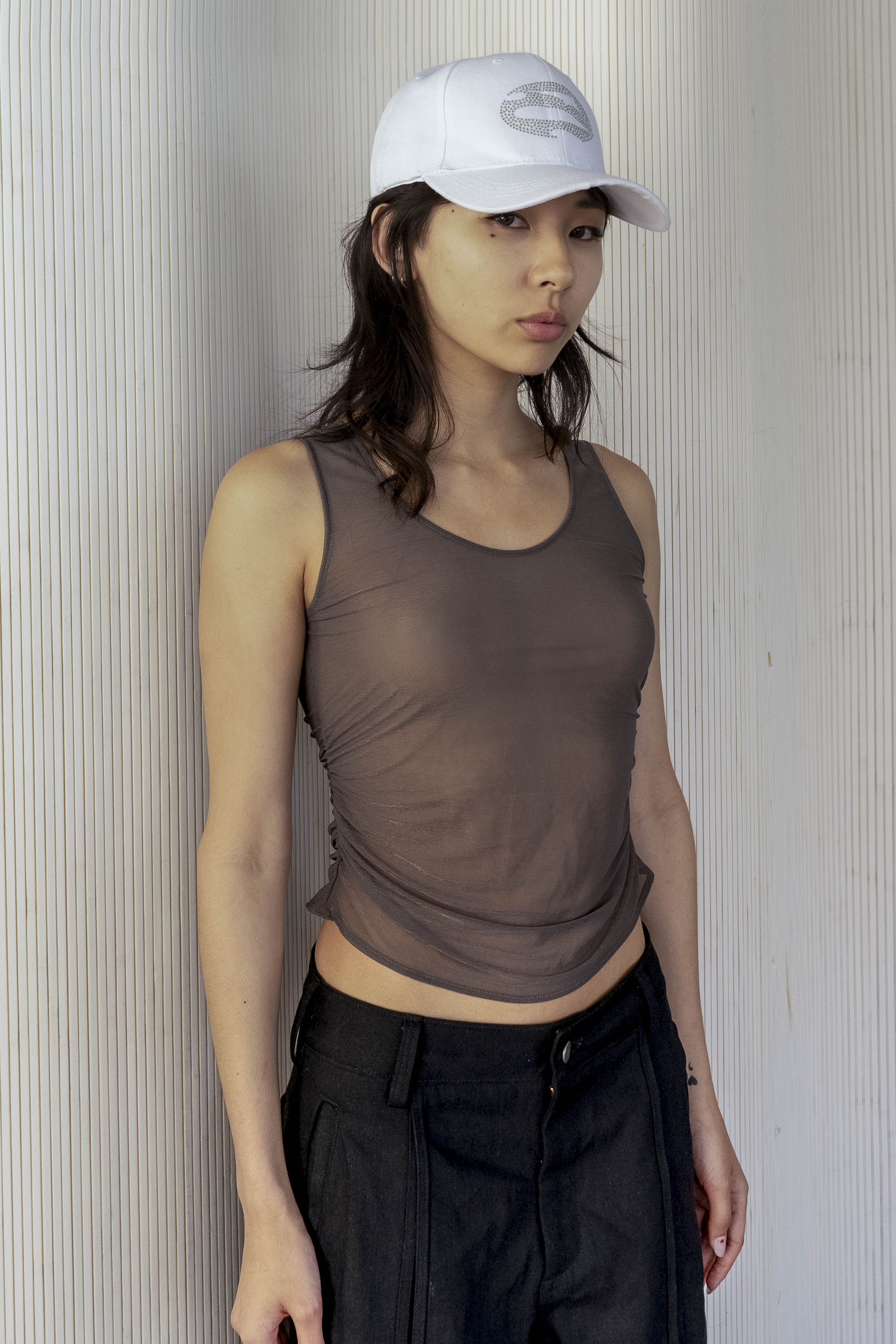 A model wearing the ruched sheer tank in an aesthetically background. 100% deadstock, Japanese sheer polyester