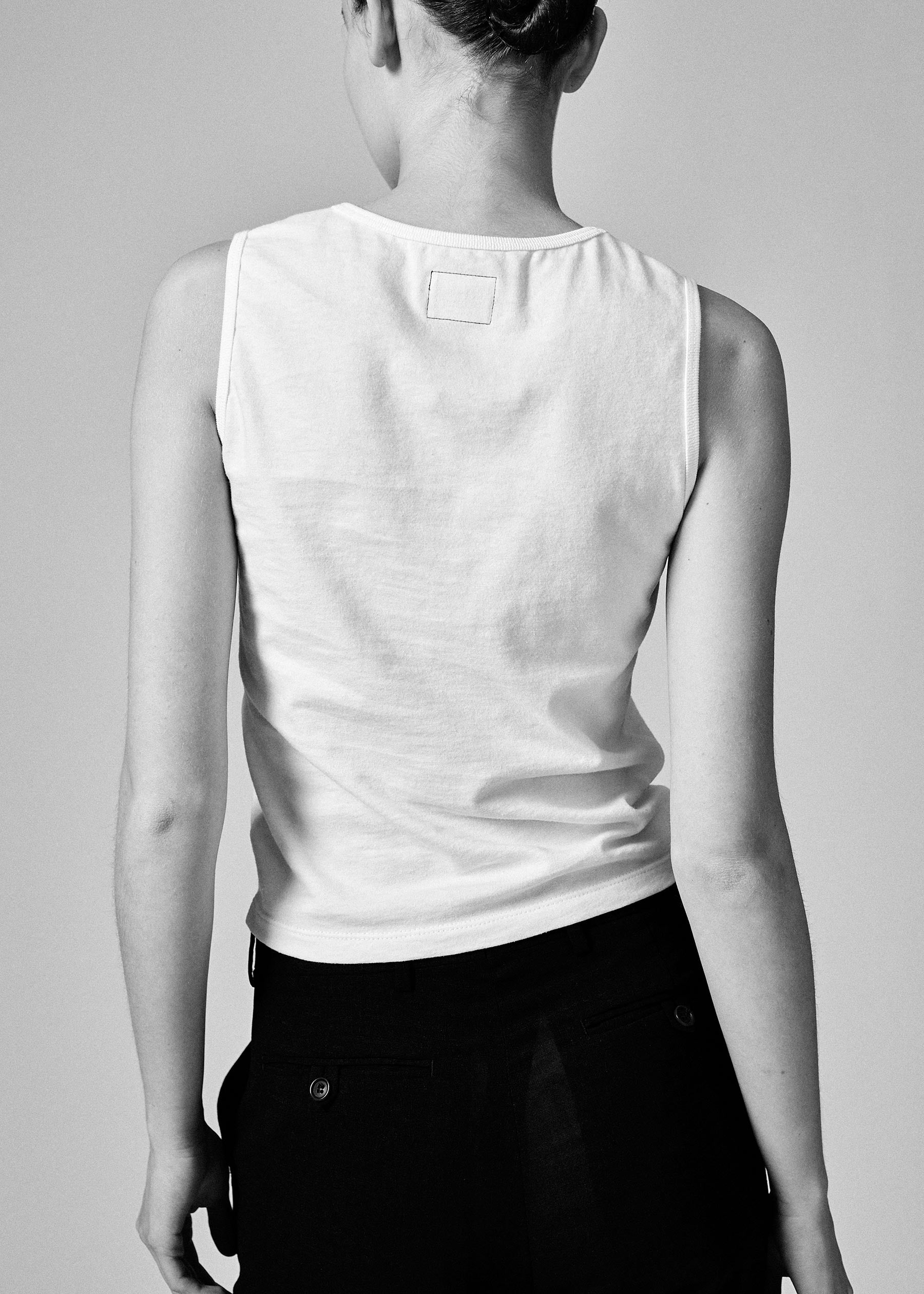 A model wearing the white 03 tank in a white background. 100% made from organic grown cotton. 