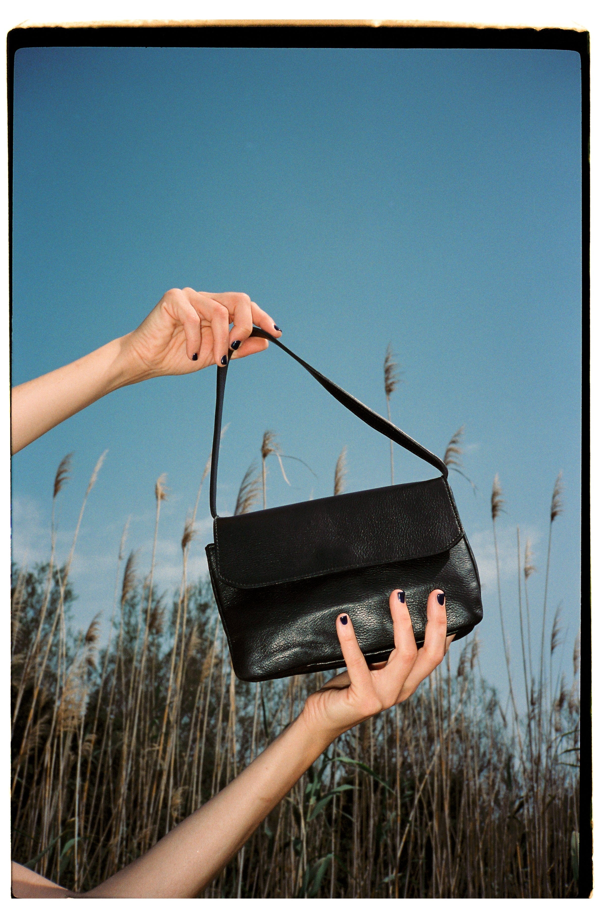 A model wearing the babe black matte bag in an aesthetically background. 100% made from deadstock leather.