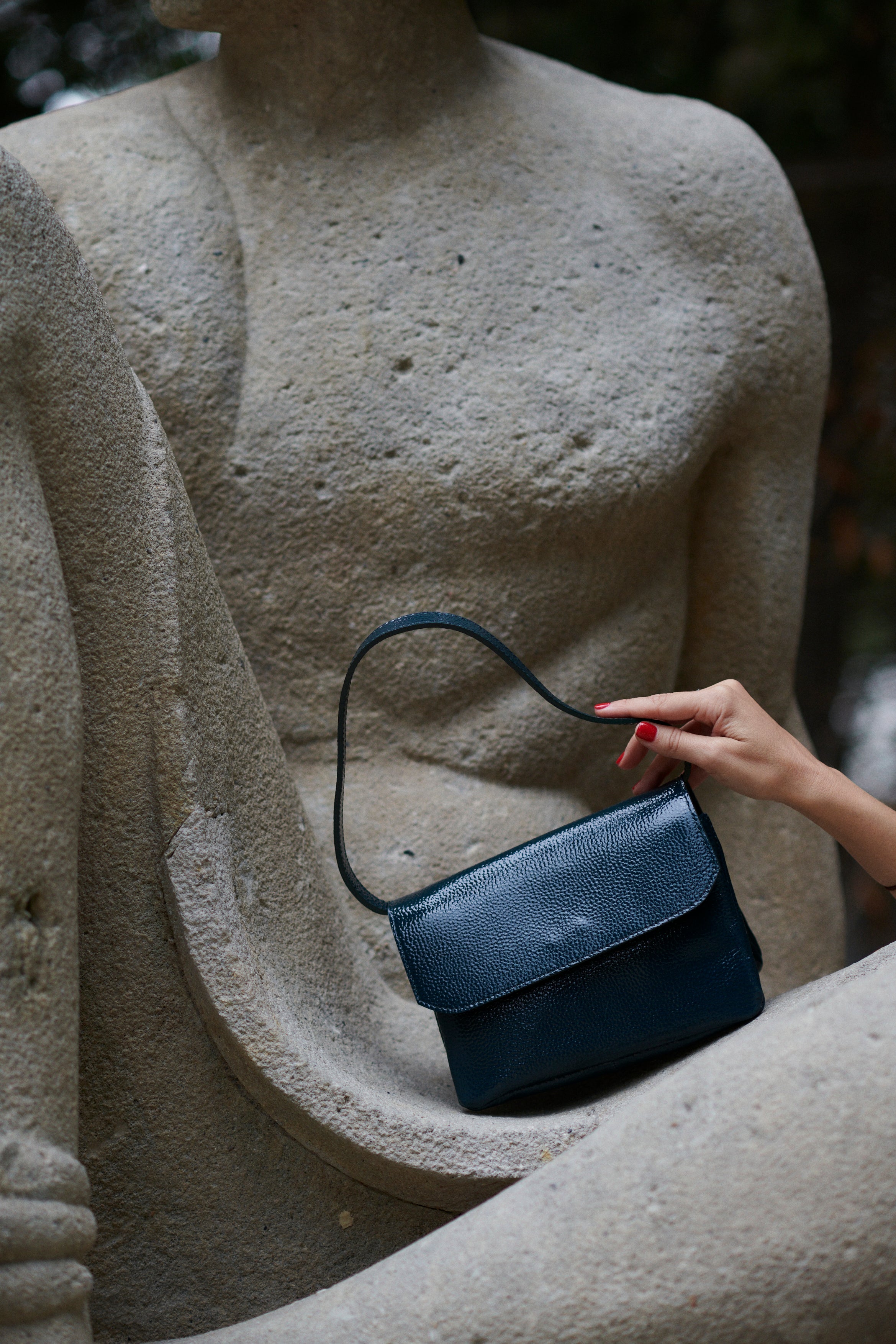A model with the babe forest green bag in an aesthetically background. 100% made from deadstock leather.