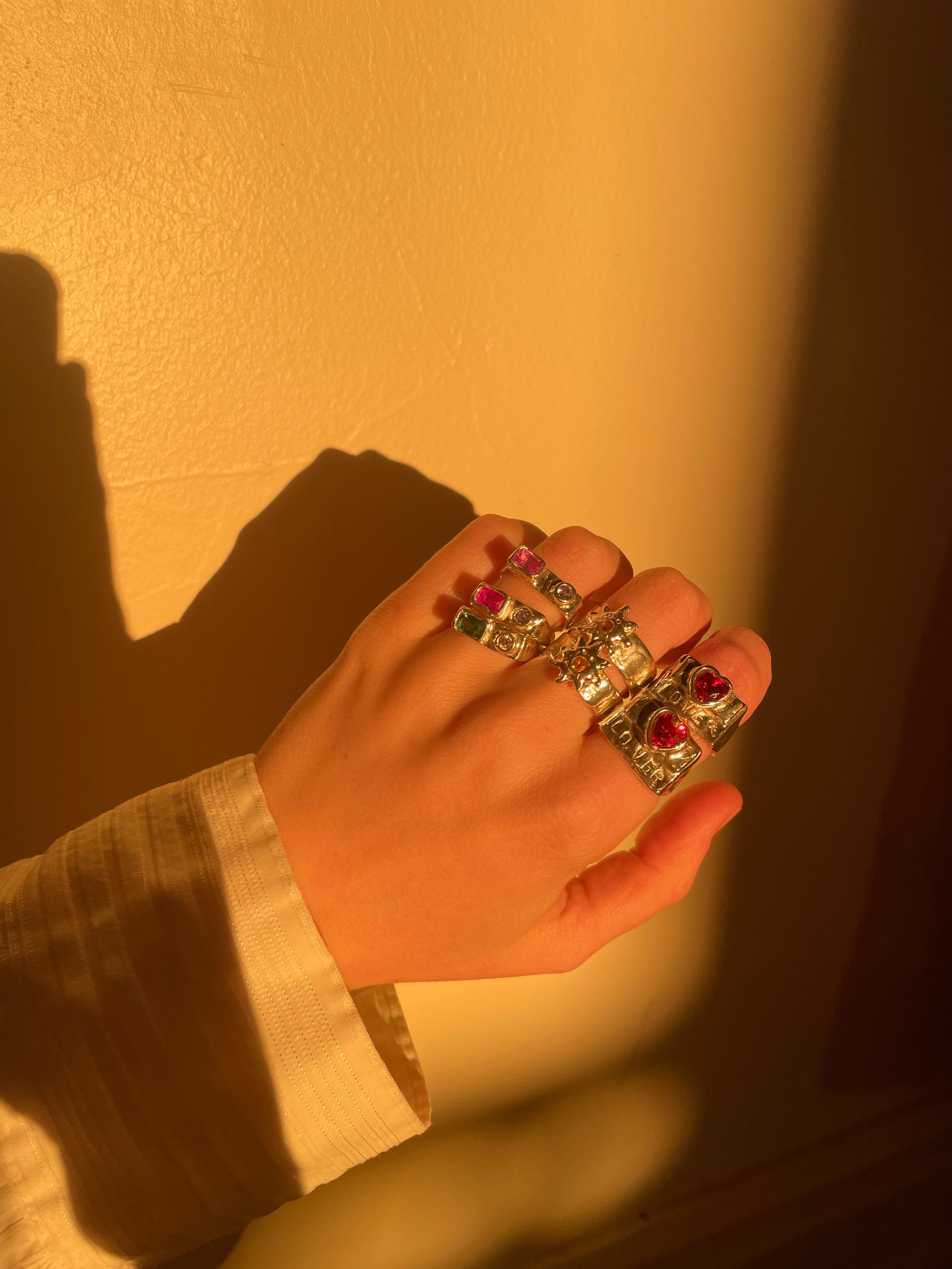 A hand model wearing the custom sun clown ring. Made from 100% recycled metals and lab created gemstones.