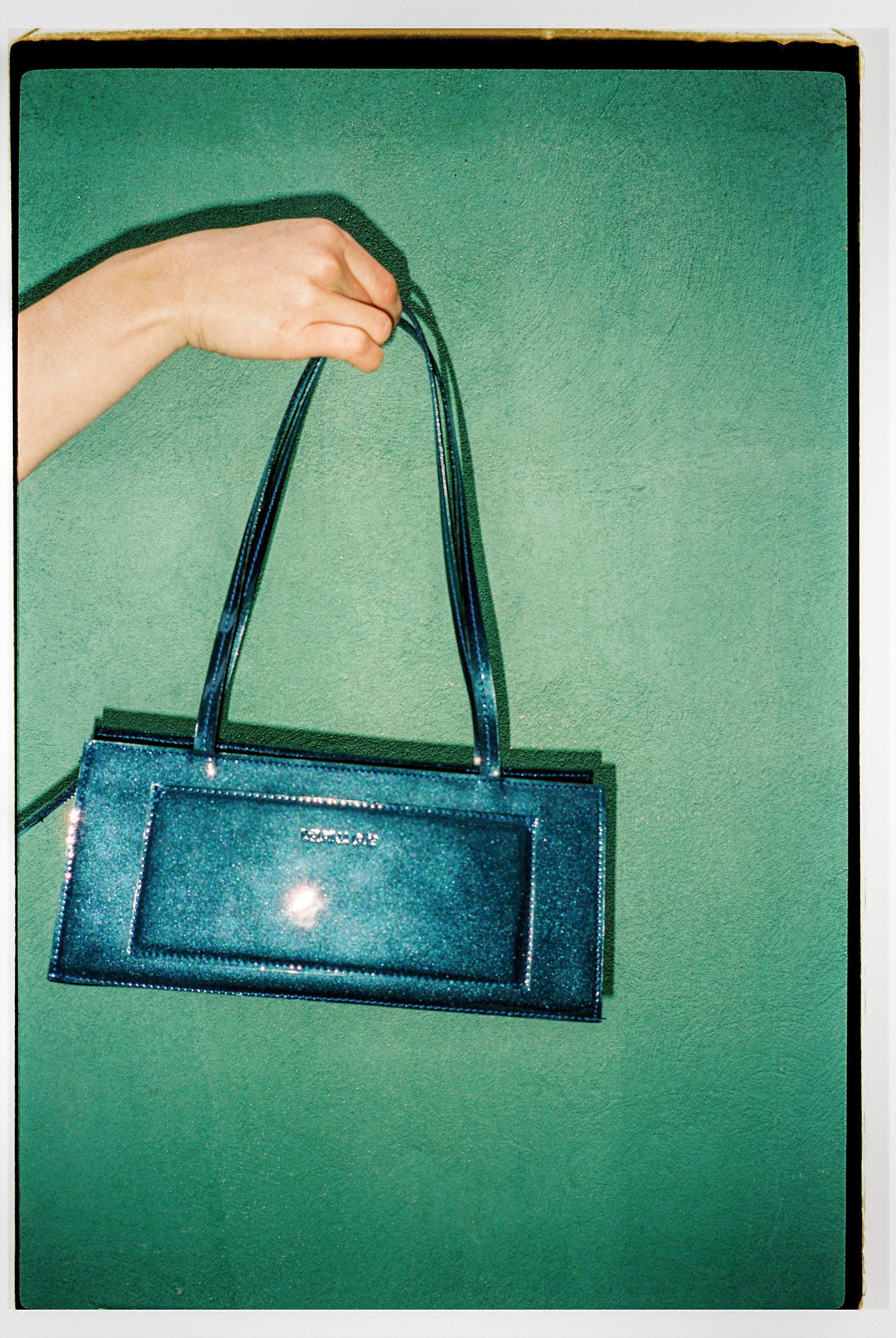 A model wearing the hotdog night blue bag in a teal background. 100% made from deadstock leather.