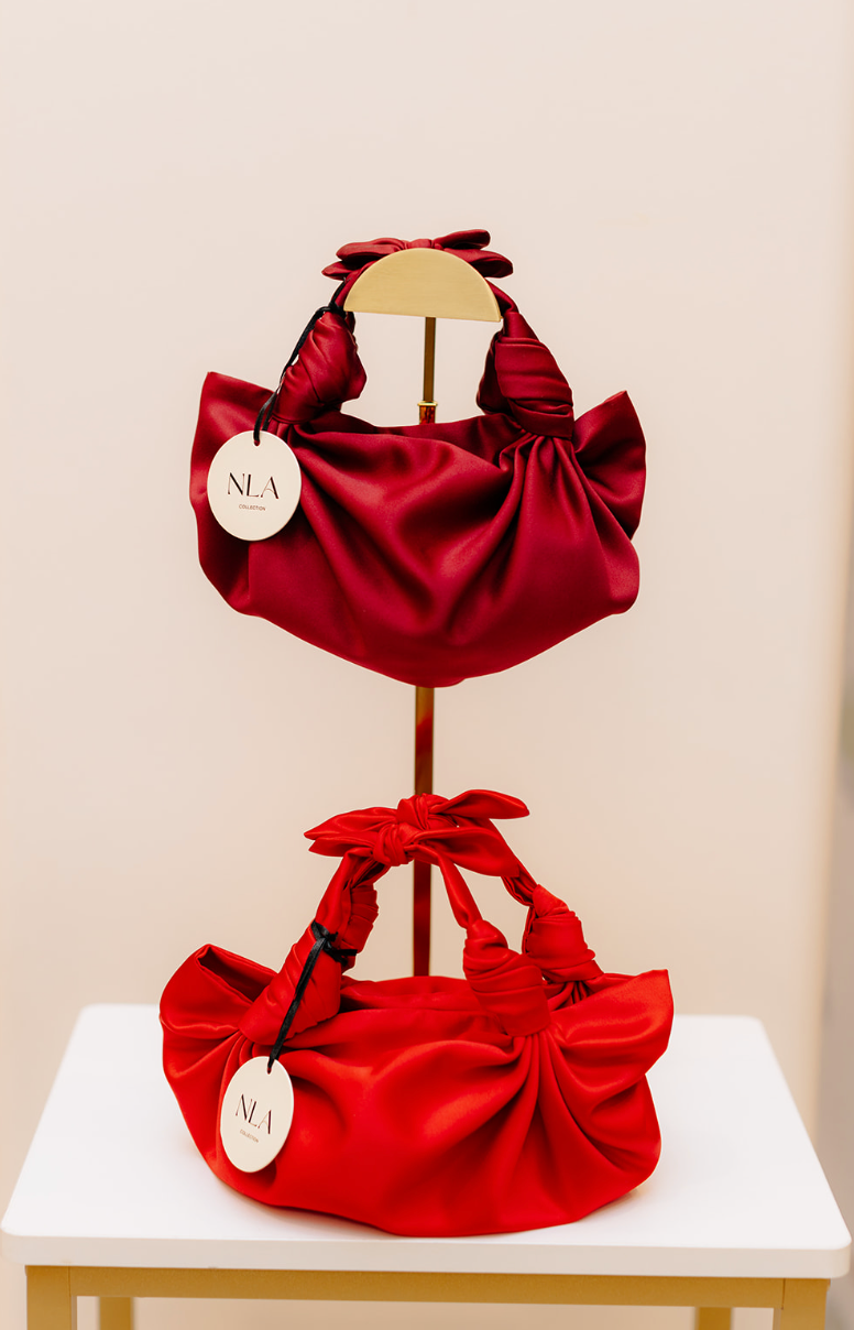 The merlot silk knot bag on display in a white background. Deadstock silky satin fabric sourced in Los Angeles.
