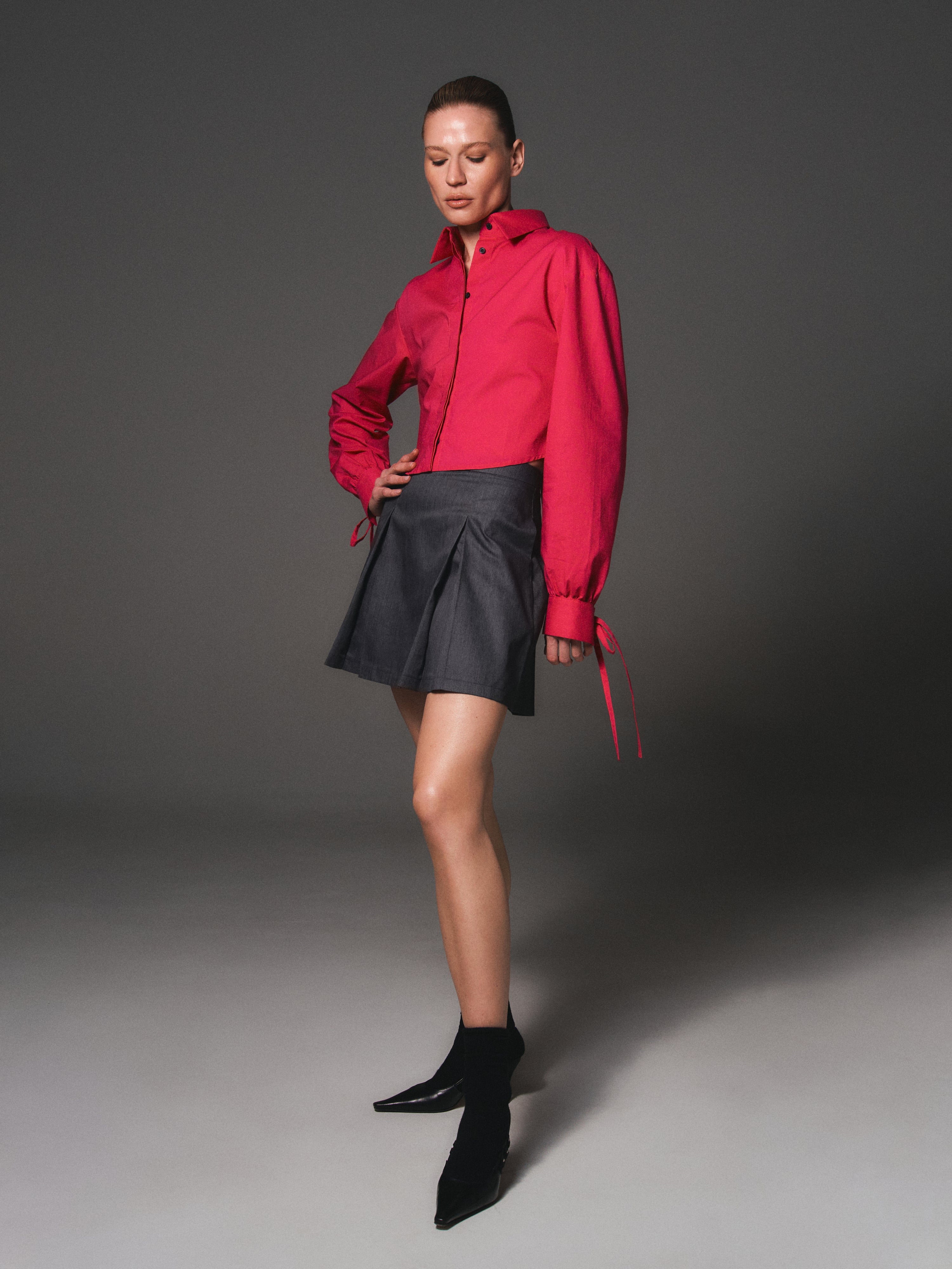 A model posing wearing an organic cotton Malva shirt and a SeaSycle skirt in grey by HER CIPHER