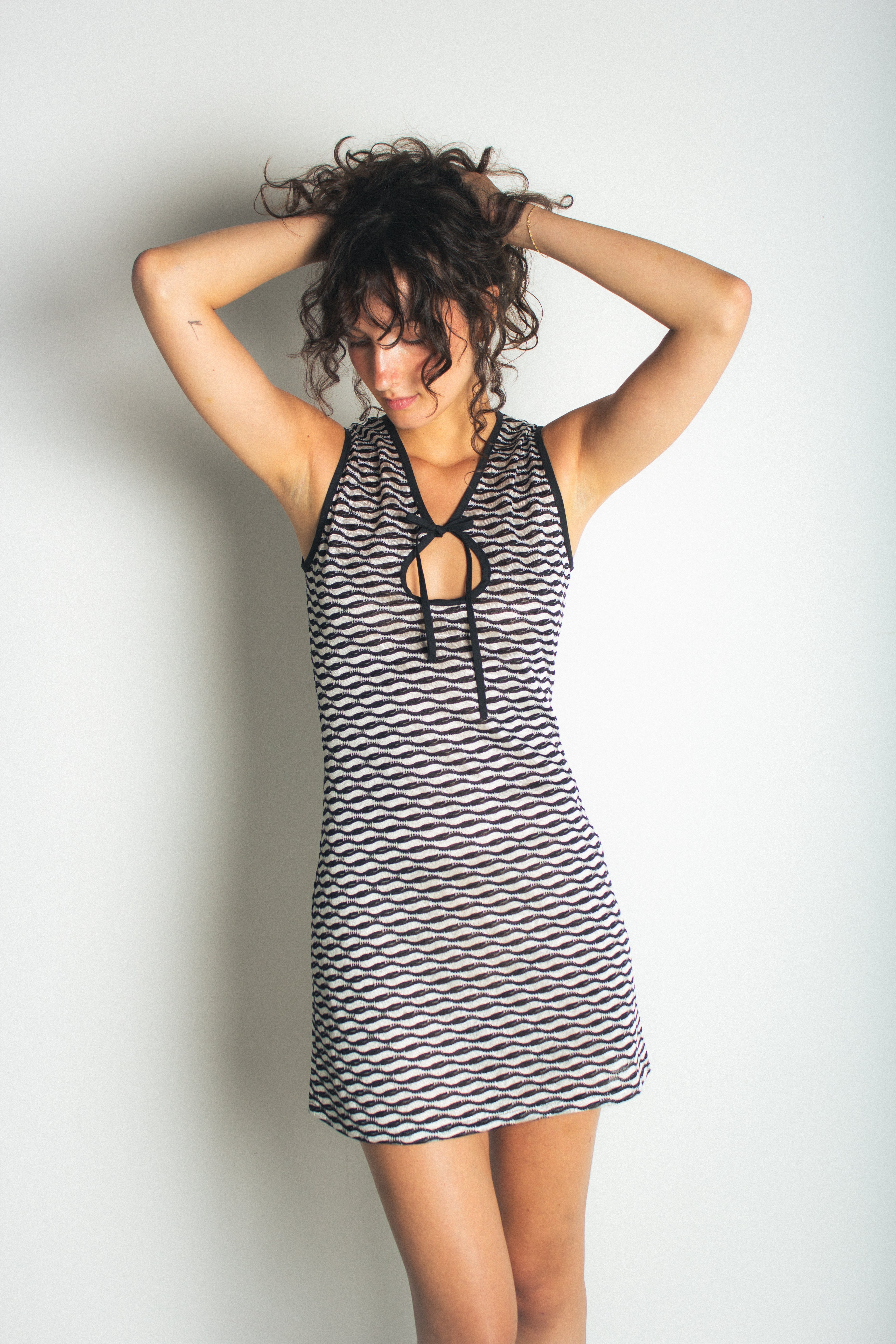 A model wearing the short demie dress in a white background. 100% deadstock Missoni-like, stretch knit blend.