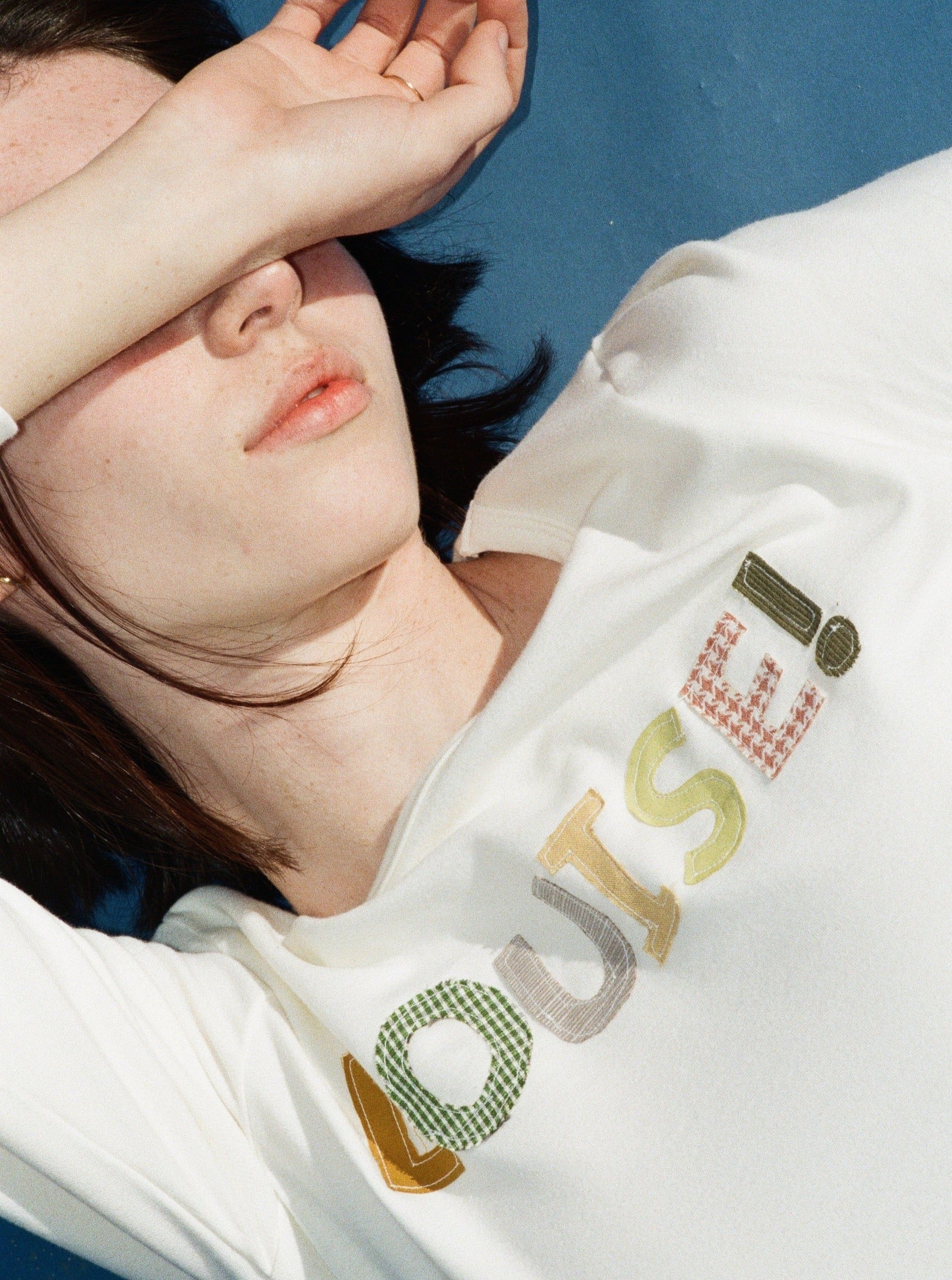 A model wearing the custom long sleeve in a blue background. Made from certified organic cotton and deadstock.